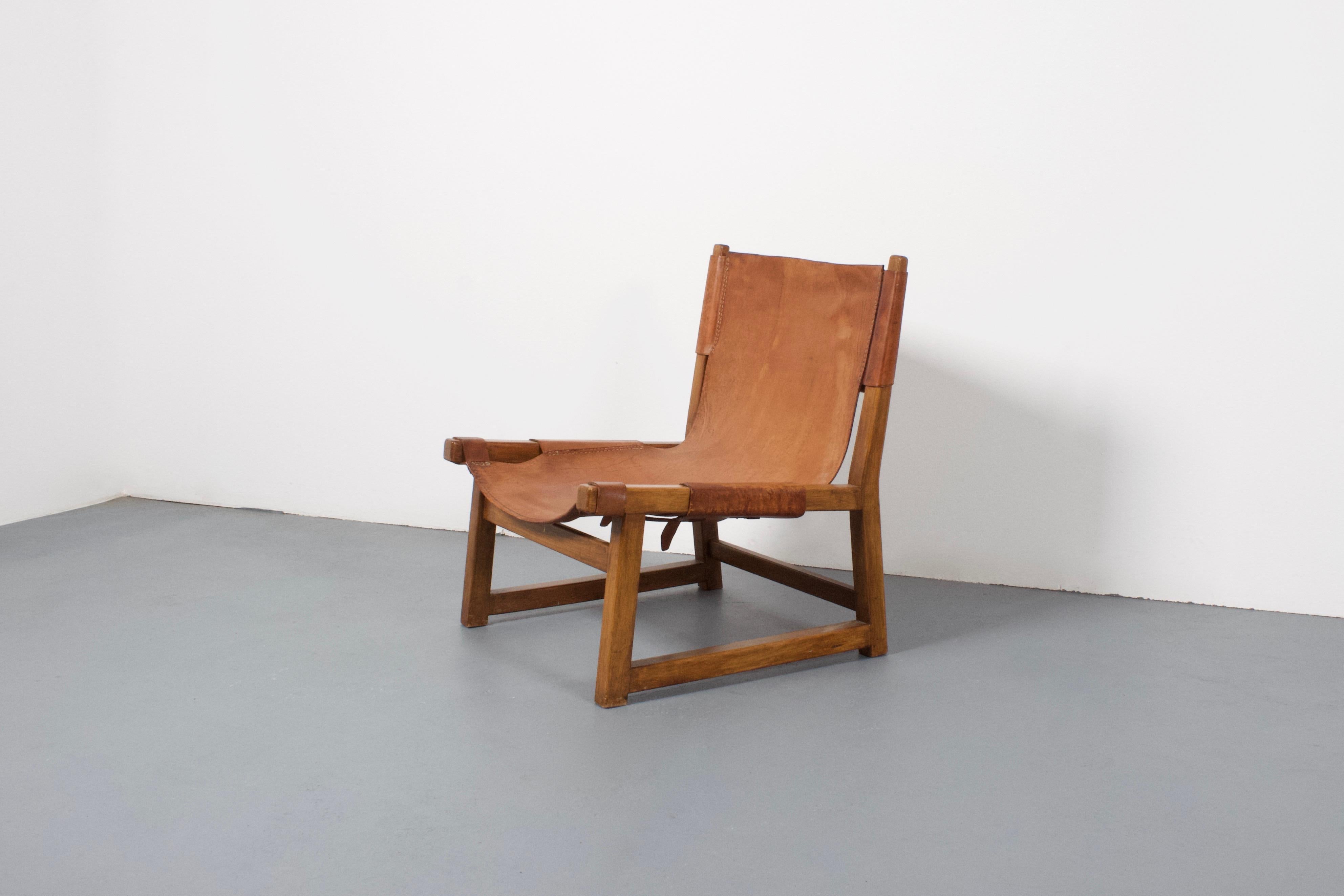 Hunting chair by Paco Muñoz in beautiful condition.

This low lounge chair has a rustic solid oak frame.

The thick cognac colored leather is loosely attached to the frame with a strap on the underside.

The leather has a great patina and is in very