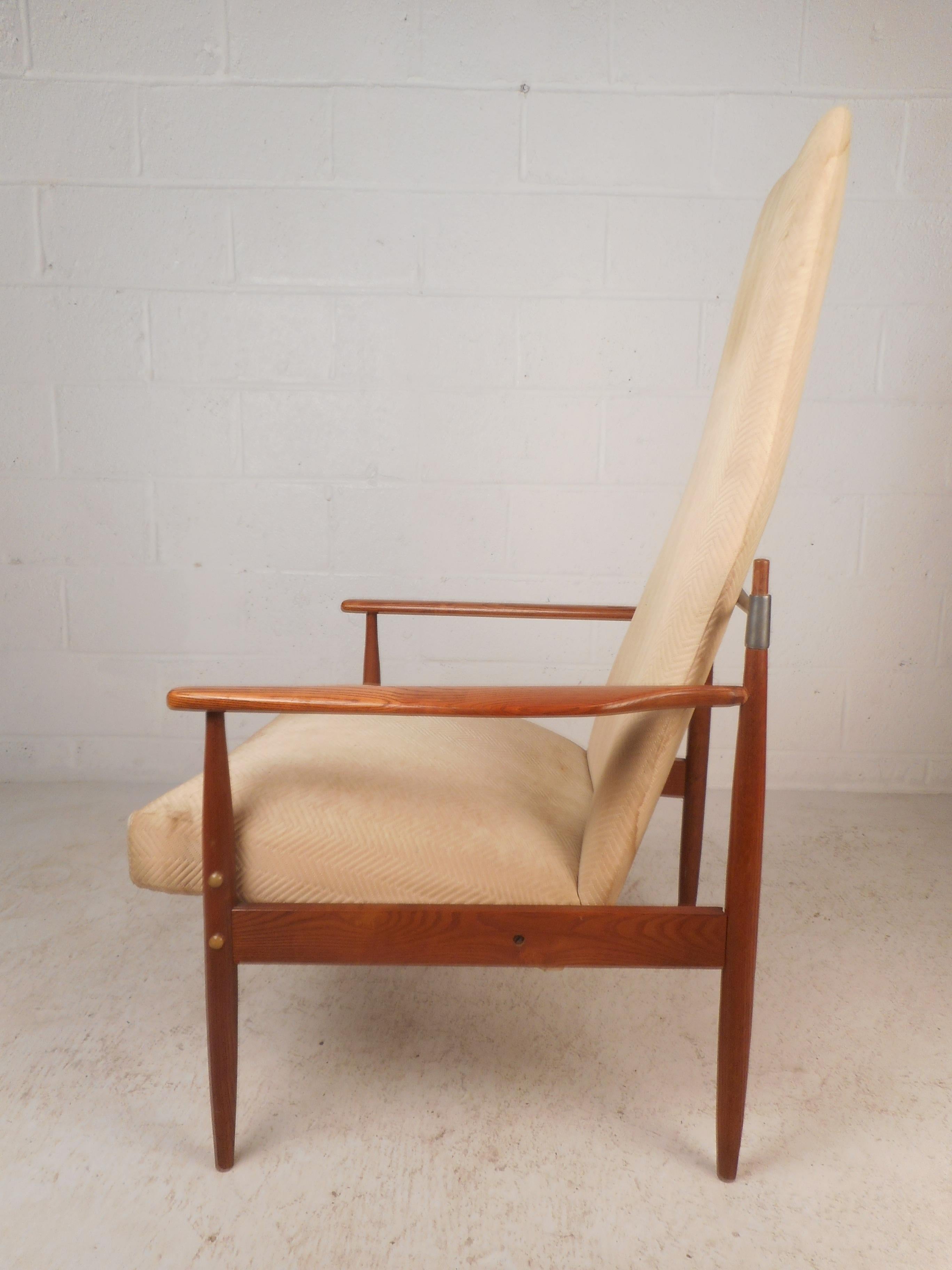 Dieser schöne Mid-Century Modern Lounge Chair hat eine hohe Rückenlehne und einen dick gepolsterten Sitz. Elegantes dänisches Design mit einem Rahmen aus geschliffenem Eichenholz und konisch zulaufenden Beinen. Dieser seltene Loungesessel im Stil