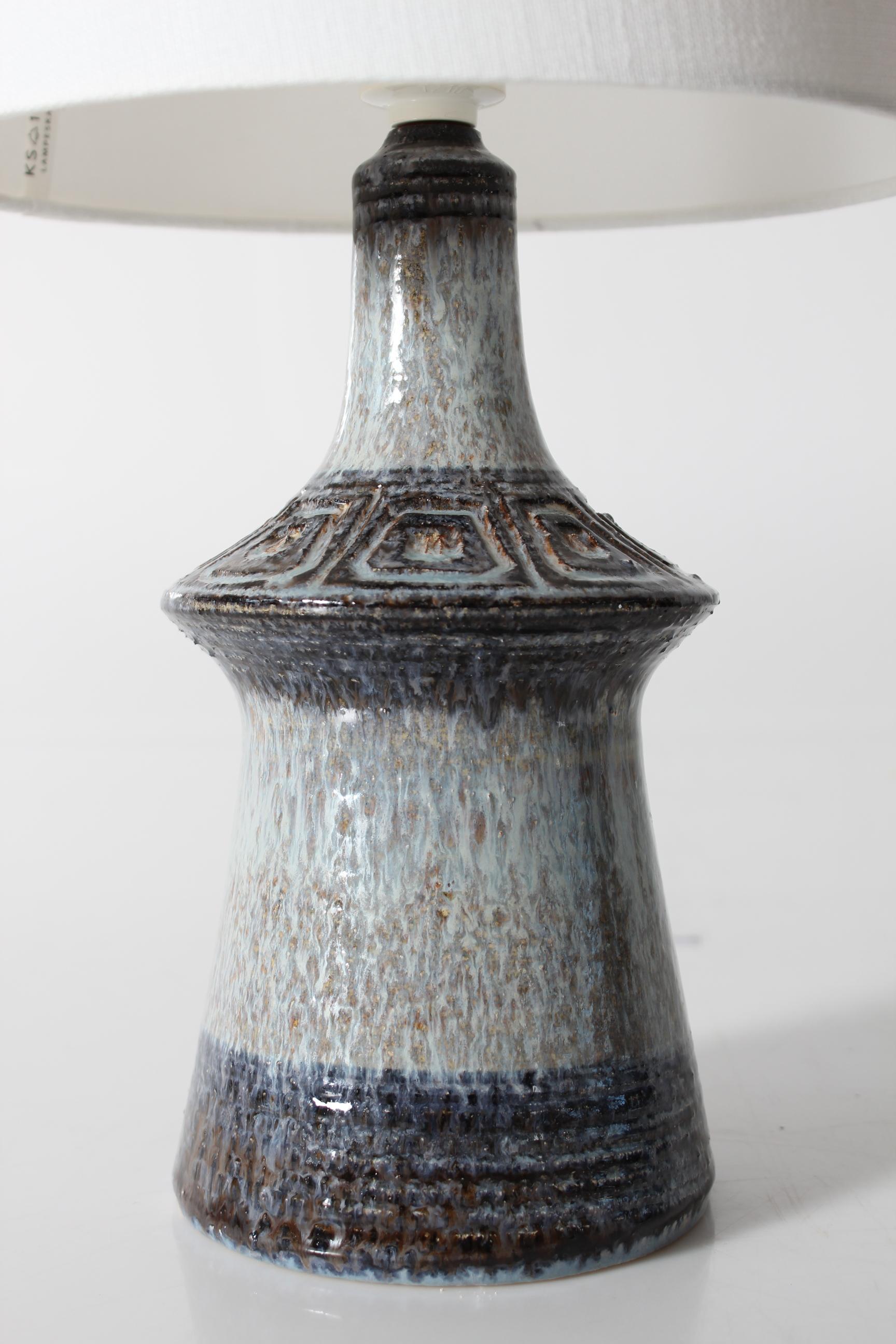 Mid-century Danish ceramic table lamp by Jette Hellerøe for the ceramic workshop Axella. Made circa 1970s.

The base is decorated with a geometric pattern covered with glossy glaze in shades of light and dark blue, gray and purple.

Included is a