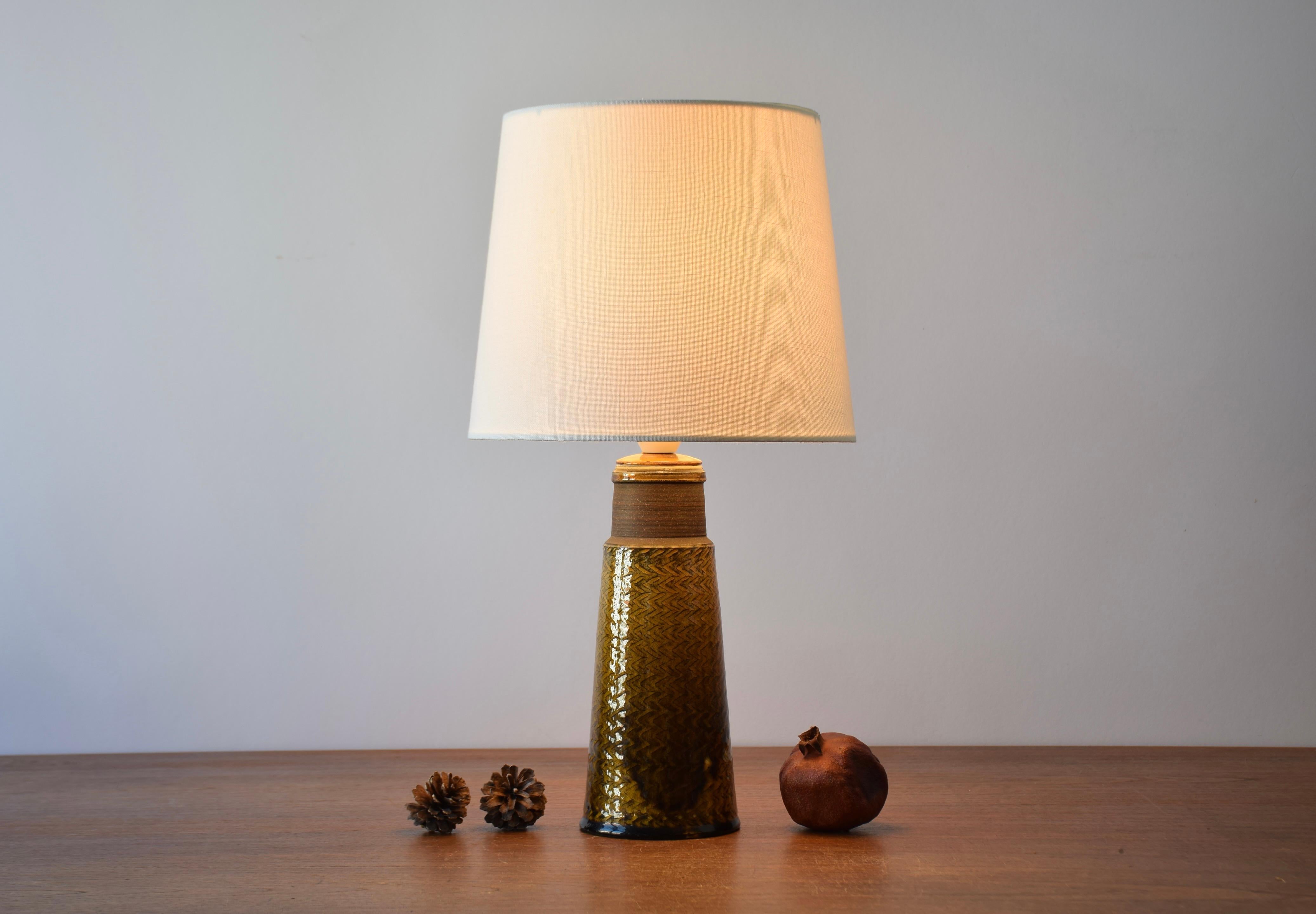 Table lamp designed by Nils Kähler and made by Herman August Kähler´s ceramic workshop in Denmark in the 1960s.

The lamp base has an incised zigzag pattern and the glossy glaze is amber / curry colored. A broad band at the top is left smooth and