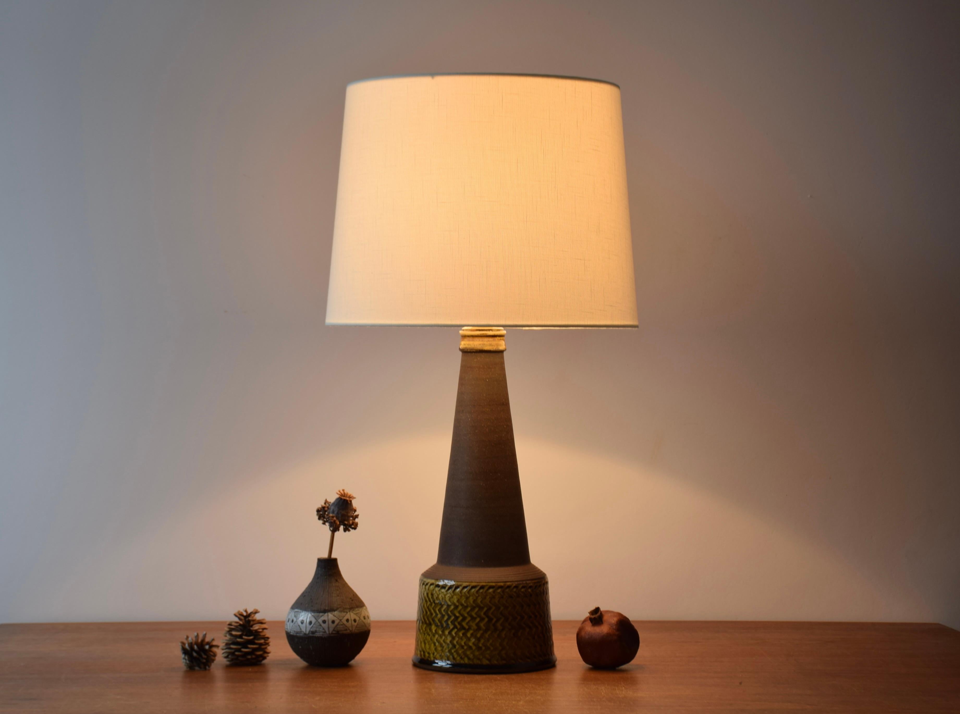 Tall table lamp by Nils Kähler from Herman August Kähler's ceramic workshop in Denmark. Made ca 1960s. 

The lamp base has an incised pattern and the glossy glaze is amber / curry colored. The neck and the shoulders are left smooth and without