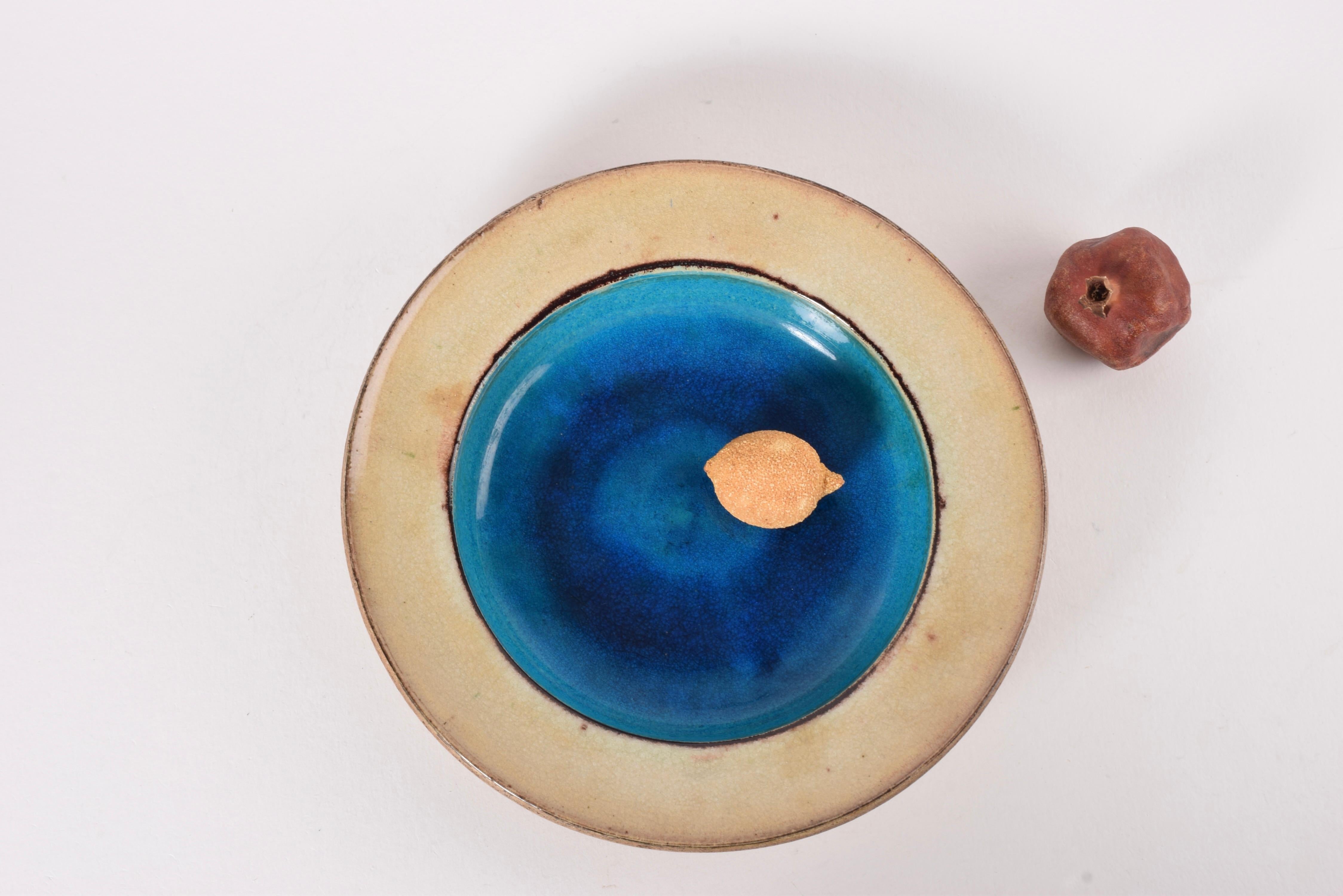 Très rare grande coupe basse de Nils Kähler pour l'atelier de céramique danois Kähler. 

Elle présente une glaçure d'un bleu turquoise profond, aussi vif qu'un océan, et un bord de glaçure beige entouré d'une accentuation irrégulière de glaçure