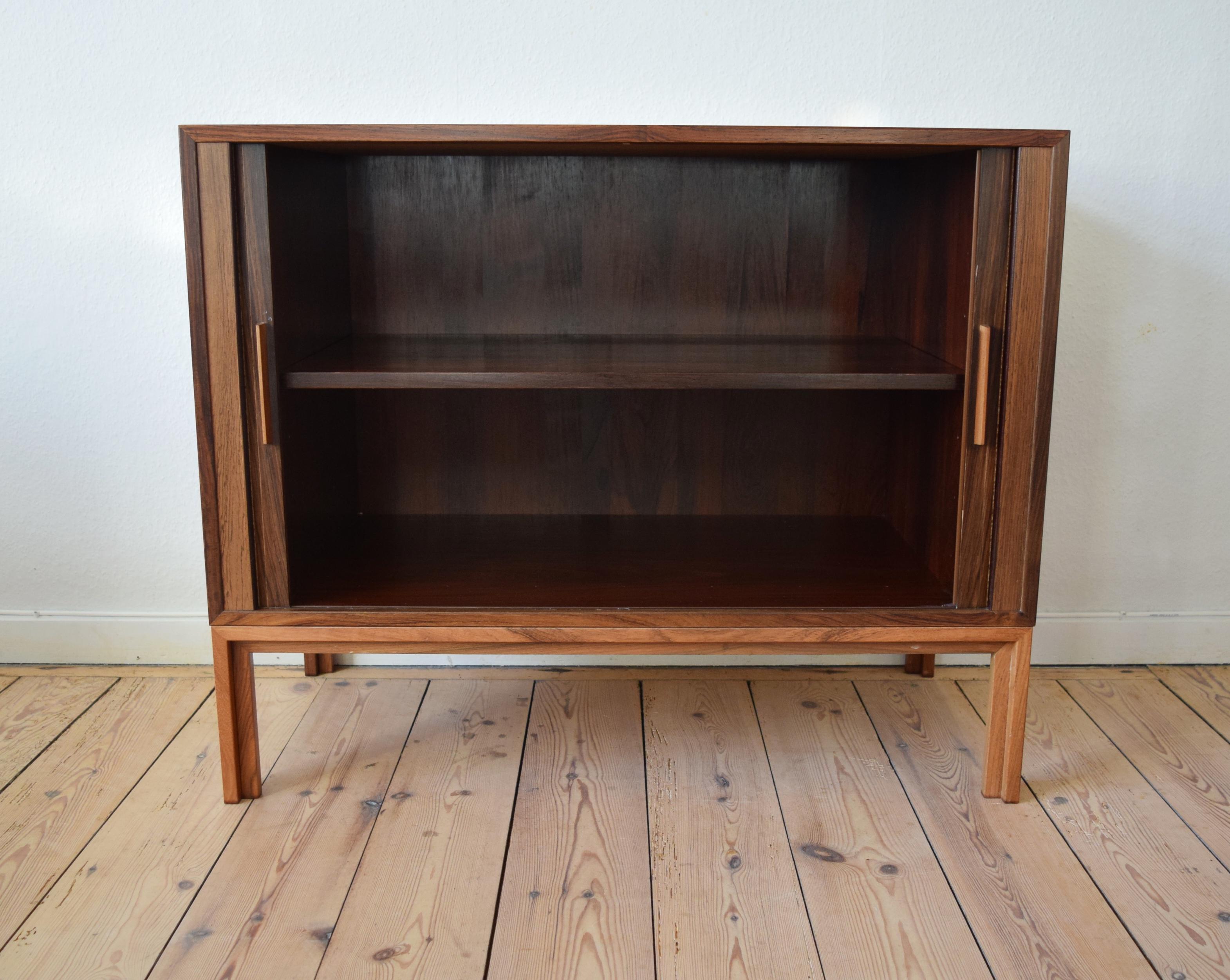 Danish rosewood bar cabinet by Kai Kristiansen for FM Møbler. Manufactured in the 1960s, this piece features two tambour doors with adjustable internal shelf. Sits on frame base solid rosewood legs. Striking rosewood grain throughout. We have more