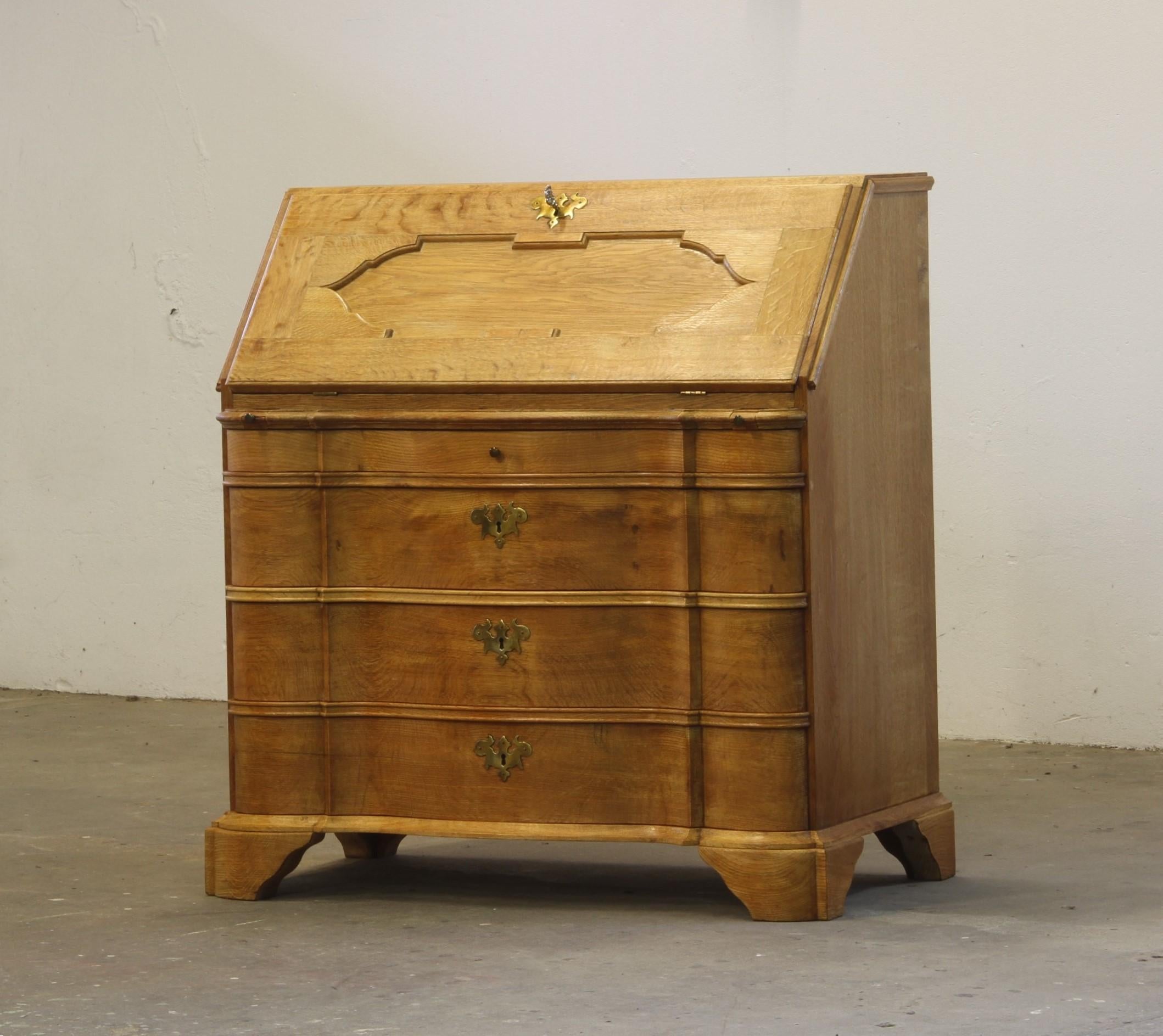 Questo scrittoio in quercia danese, realizzato negli anni '60 nello stile di Henning Kjærnulf, è un vero capolavoro che fonde senza sforzo il fascino del barocco brutalista con l'eleganza moderna della metà del secolo. Il suo robusto corpo in rovere