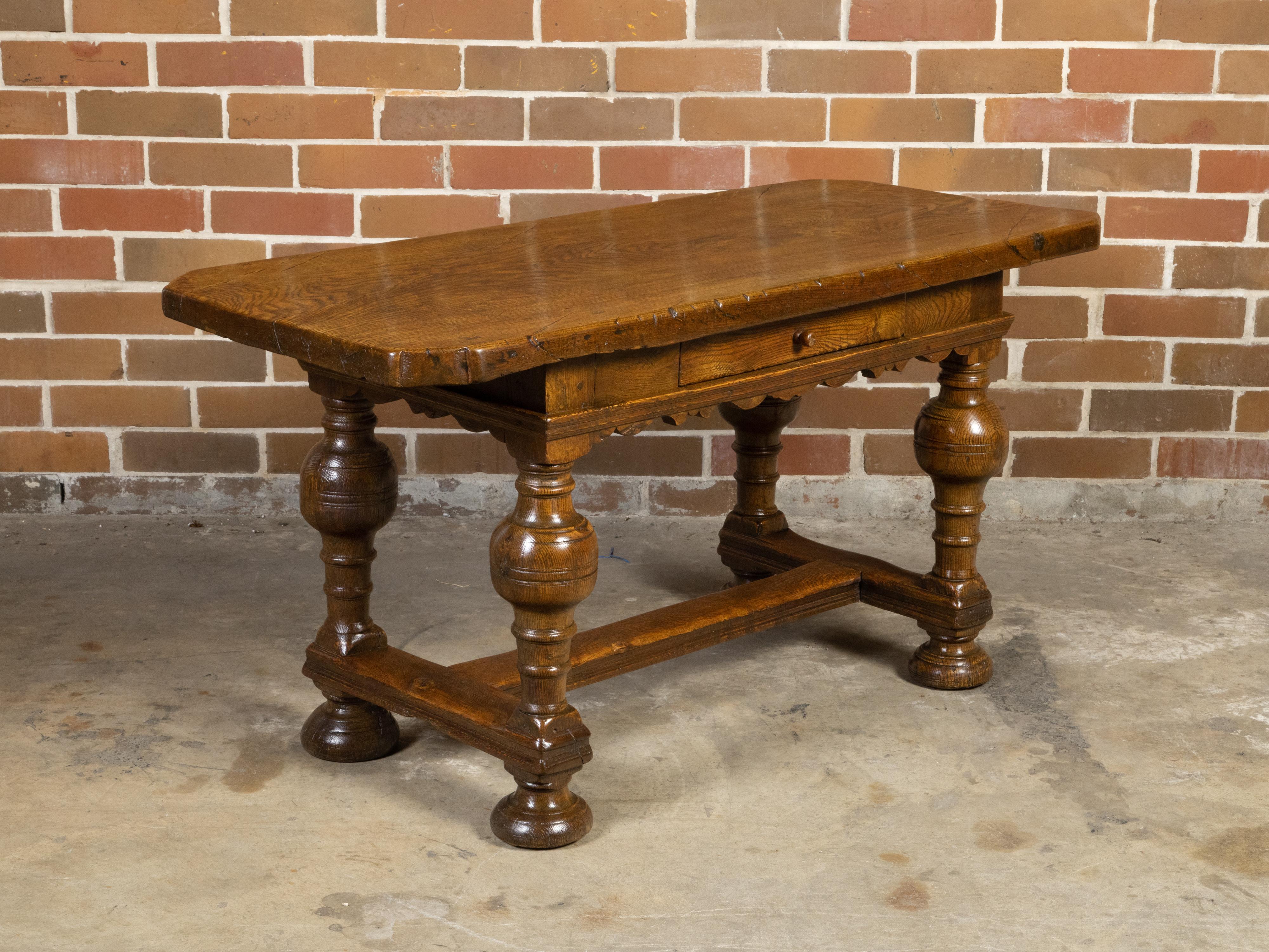 A Southern Danish Baroque style oak center table from the 19th century, with single drawer, carved apron and turned legs. Created on the Danish island of Langeland during the later years of the 19th century, this oak table features a removable