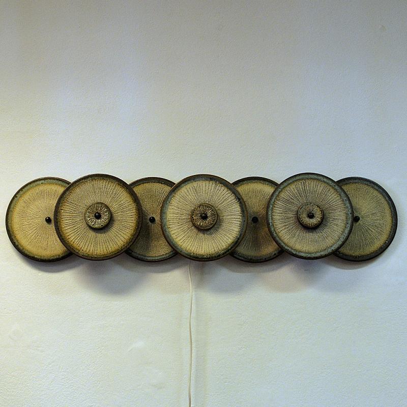 A stunning wall light sculpture of seven ceramic plates by Noomi Backhausen and Poul Brandborg for Søholm Keramik, Bornholm Denmark in the 1960s. Beautifully glazed earth colored stoneware with rippled texture in front. Beautiful light flowing out