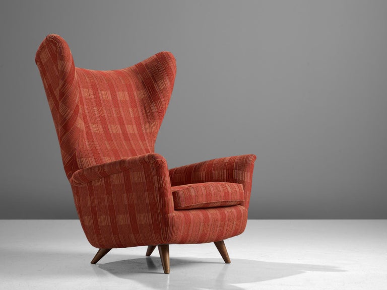 Large wingback armchair, red and orange fabric, wood, Italy, 1950s.

This Classic Italian Postwar wingback chair has an unusually high back and gracious wings that contain dramatized pointed corners. The elegant armrests are slightly curved outwards