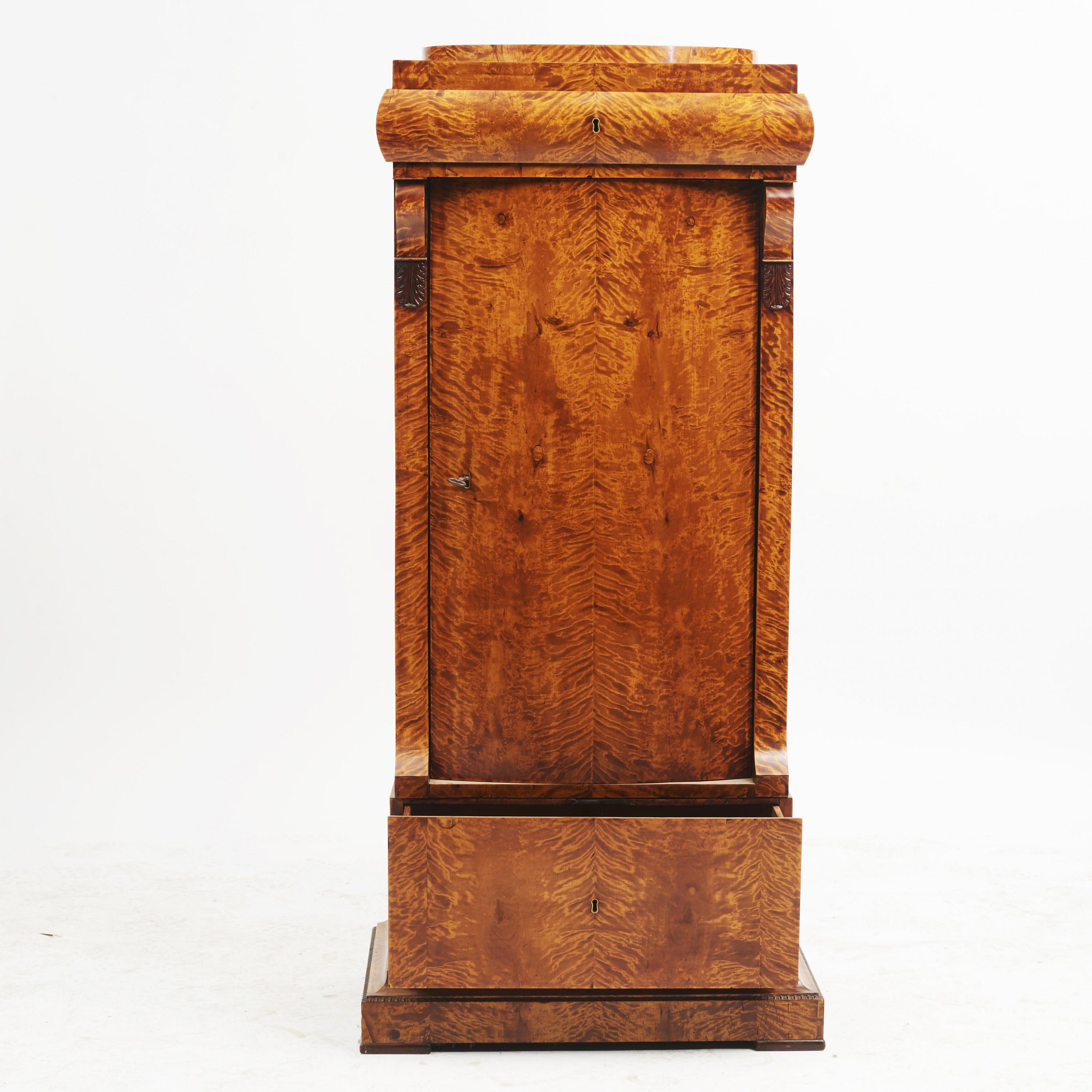 19th century Danish late Empire (Biedermeier) pedestal cabinet. Veneered with flamed birch.
Curved door. Oval top with a drawer underneath. One-drawer at the bottom.
Denmark, circa 1820-1830.

Measurement (cm): H 143, W 63, D 40.5.