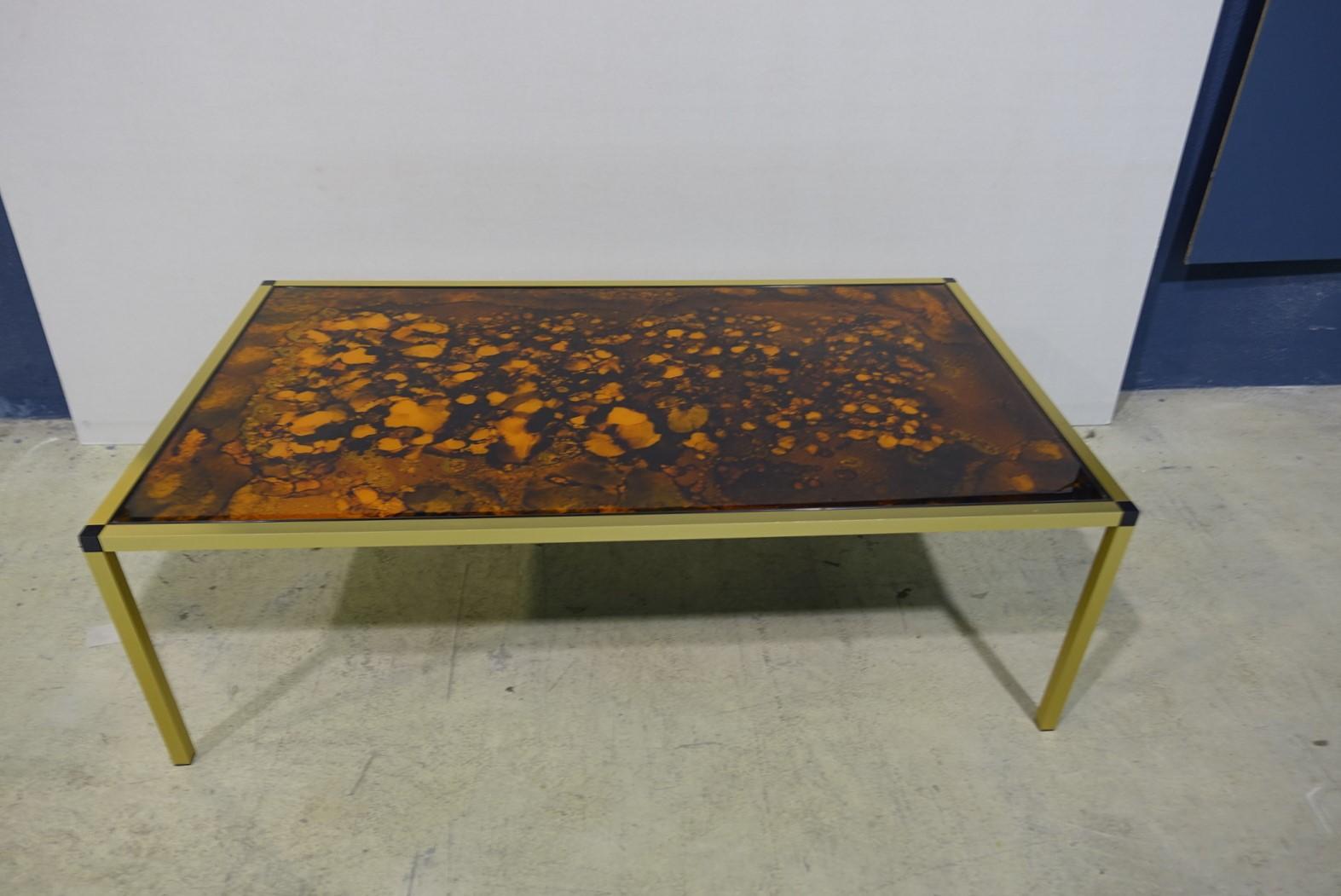 This Danish Lava pattern coffee table is made from gold aluminum with black feet and multicolored glass.