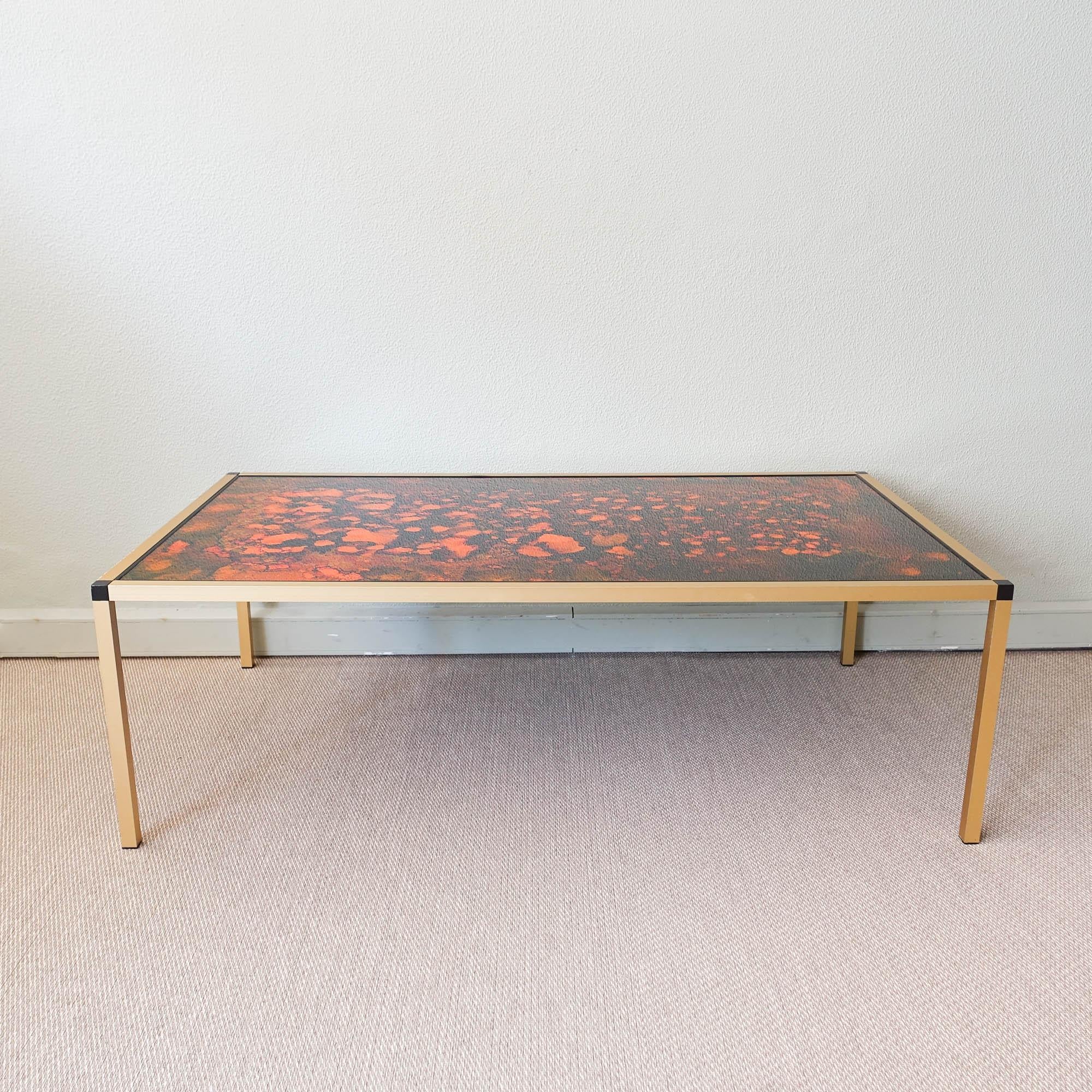 Introduce a unique and stylish addition to your living room with this stunning Danish Lava pattern coffee table from the 1970s. Manufactured in Denmark, it boasts a gold aluminum frame and black feet, which create a striking contrast against the