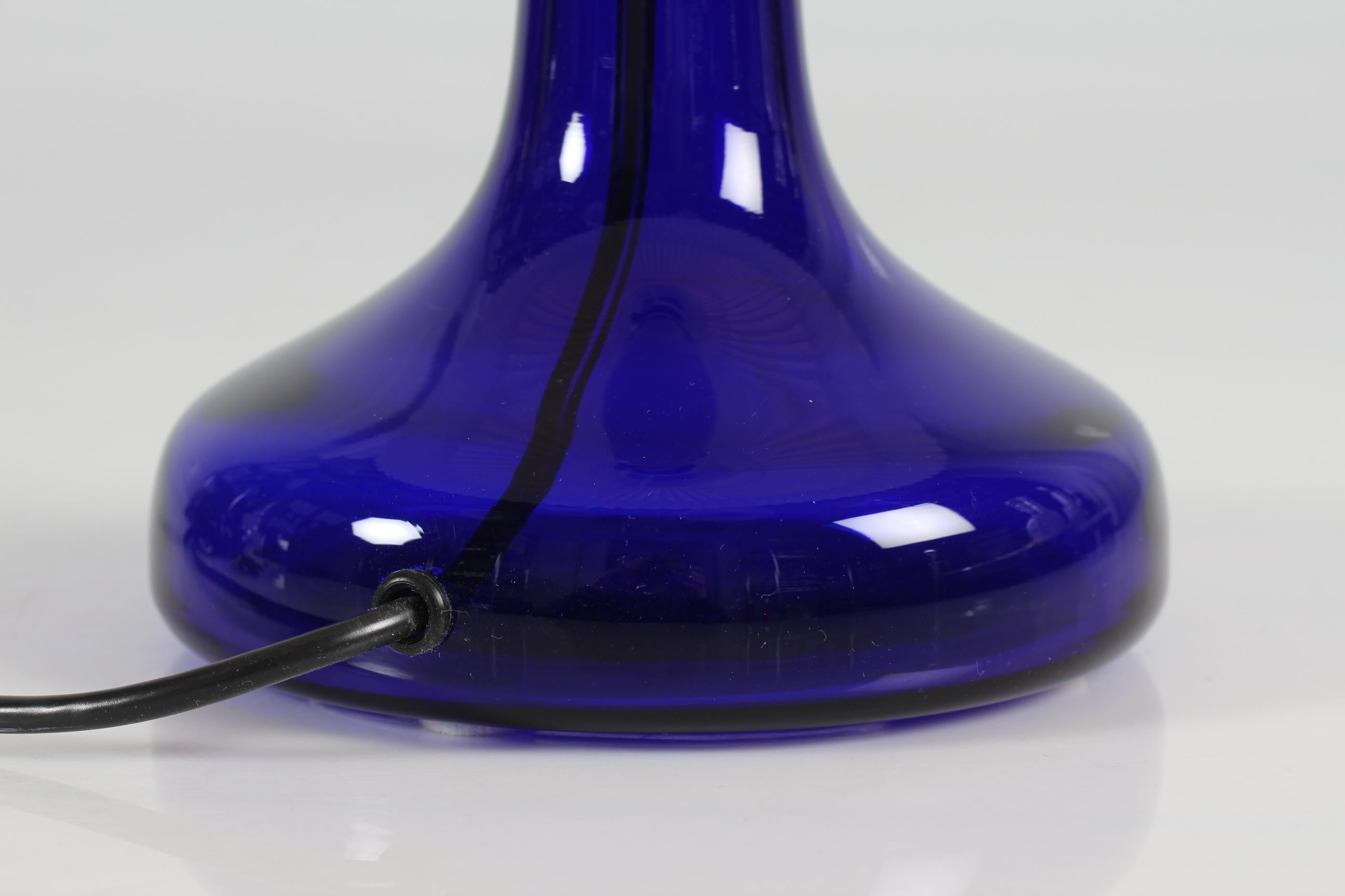 Danish table lamp model 343 by designer by Biilmann-Petersen 
The lamp foot is made of mouth blown translucent dark blue glass from Holmegaard glass works and comes with a vintage original Le Klint lamp shade.

Measurements:
Height including