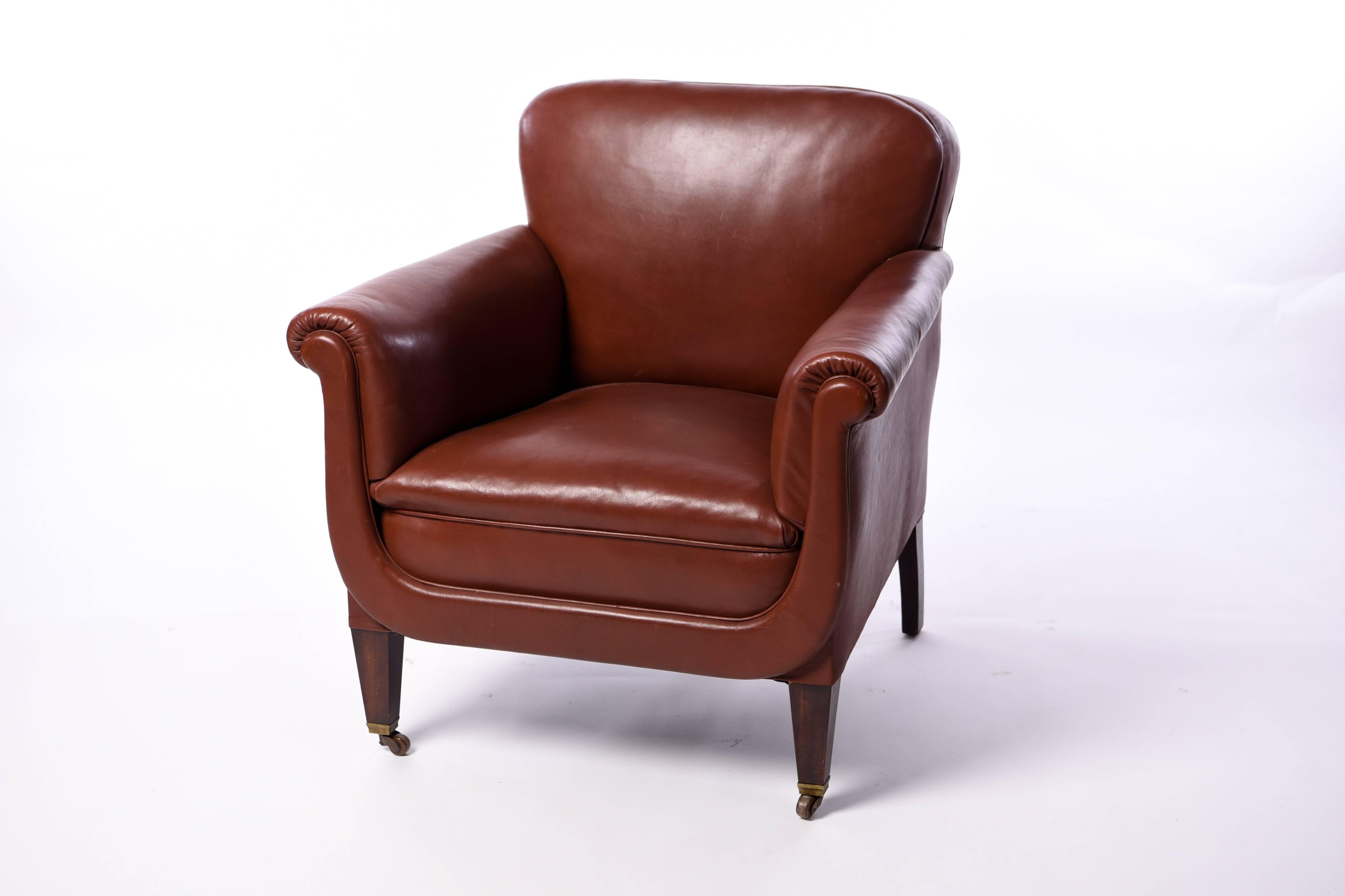 This club chair is upholstered in an earthy red leather and sits on casters which make for convenient mobility.