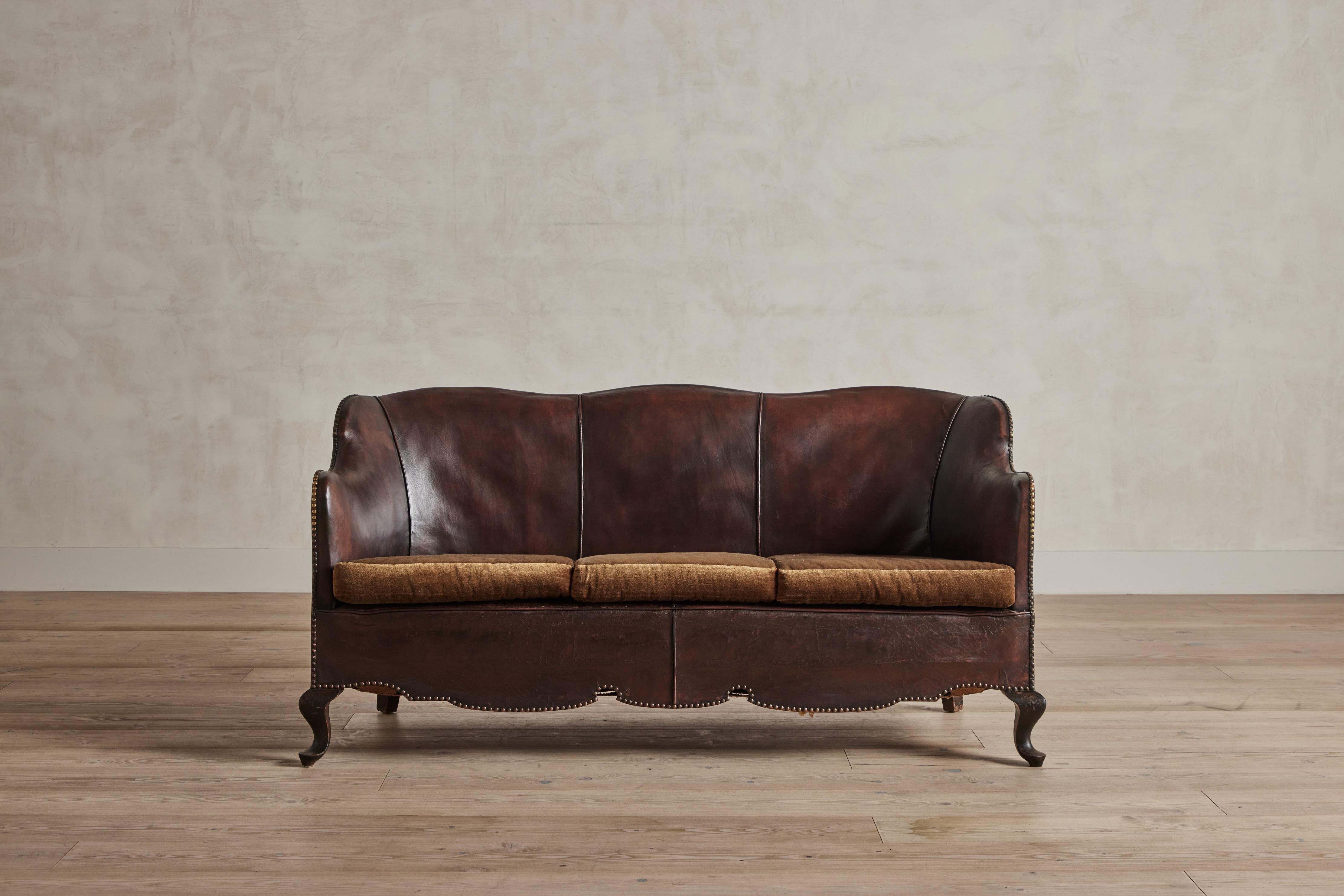 Leather sofa with velvet cushions and brass head detailing from Denmark circa 1910. Original manufacturer metal tag on the back reads 