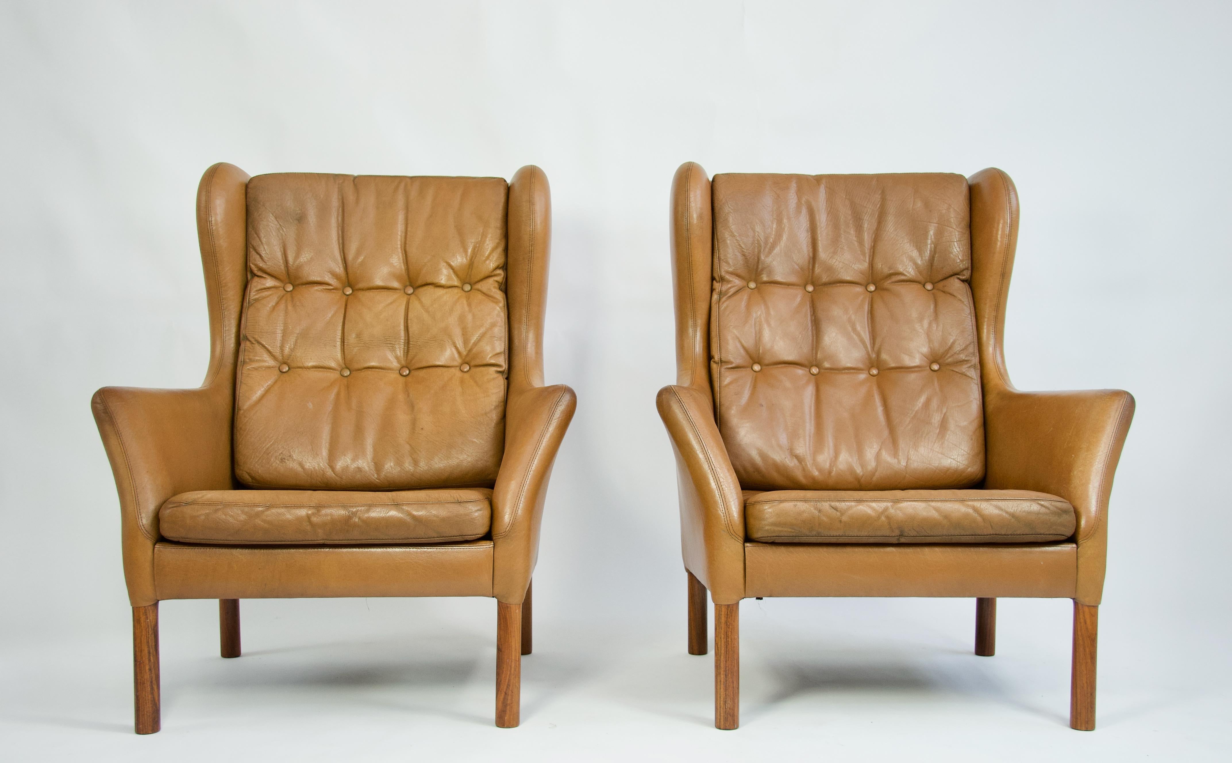 Pair of Danish high back lounge chairs with original leather. Tufted cushions. Rosewood legs.