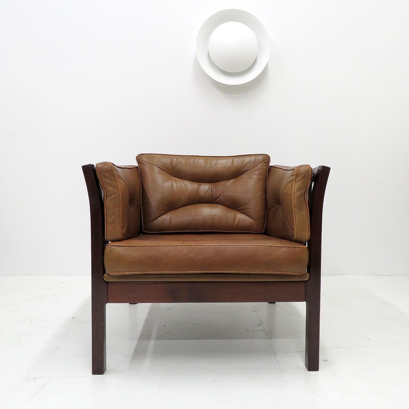 Wonderful, compact Danish Modern lounge chair, designed in 1960, dark stained beech frame with leather straps and thick leather upholstery.