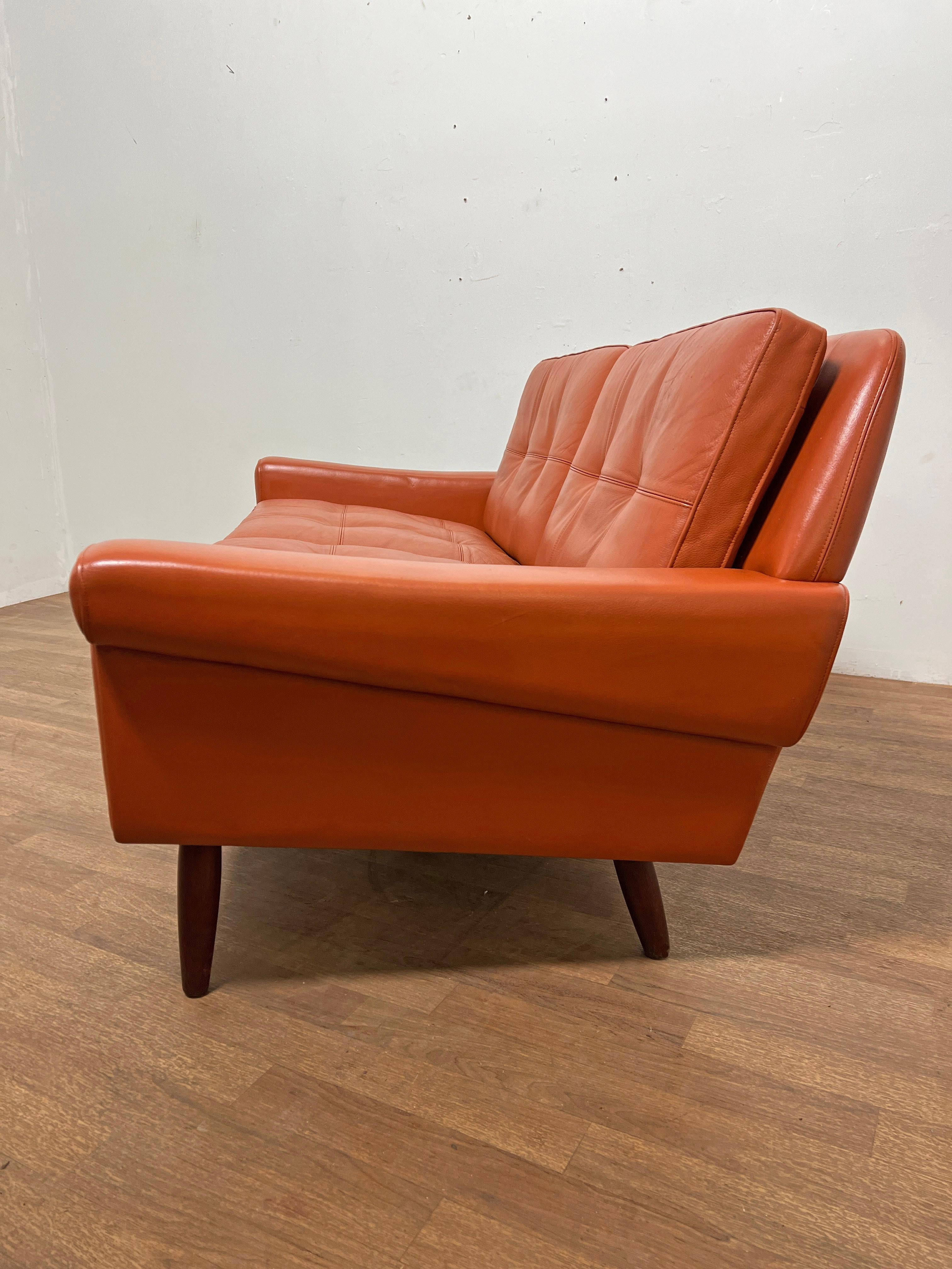 A 1960s loveseat in original cordovan leather and teak legs by Svend Skipper Mobelfabrik, Denmark.  A matching pair of lounge chairs are available in a separate listing.