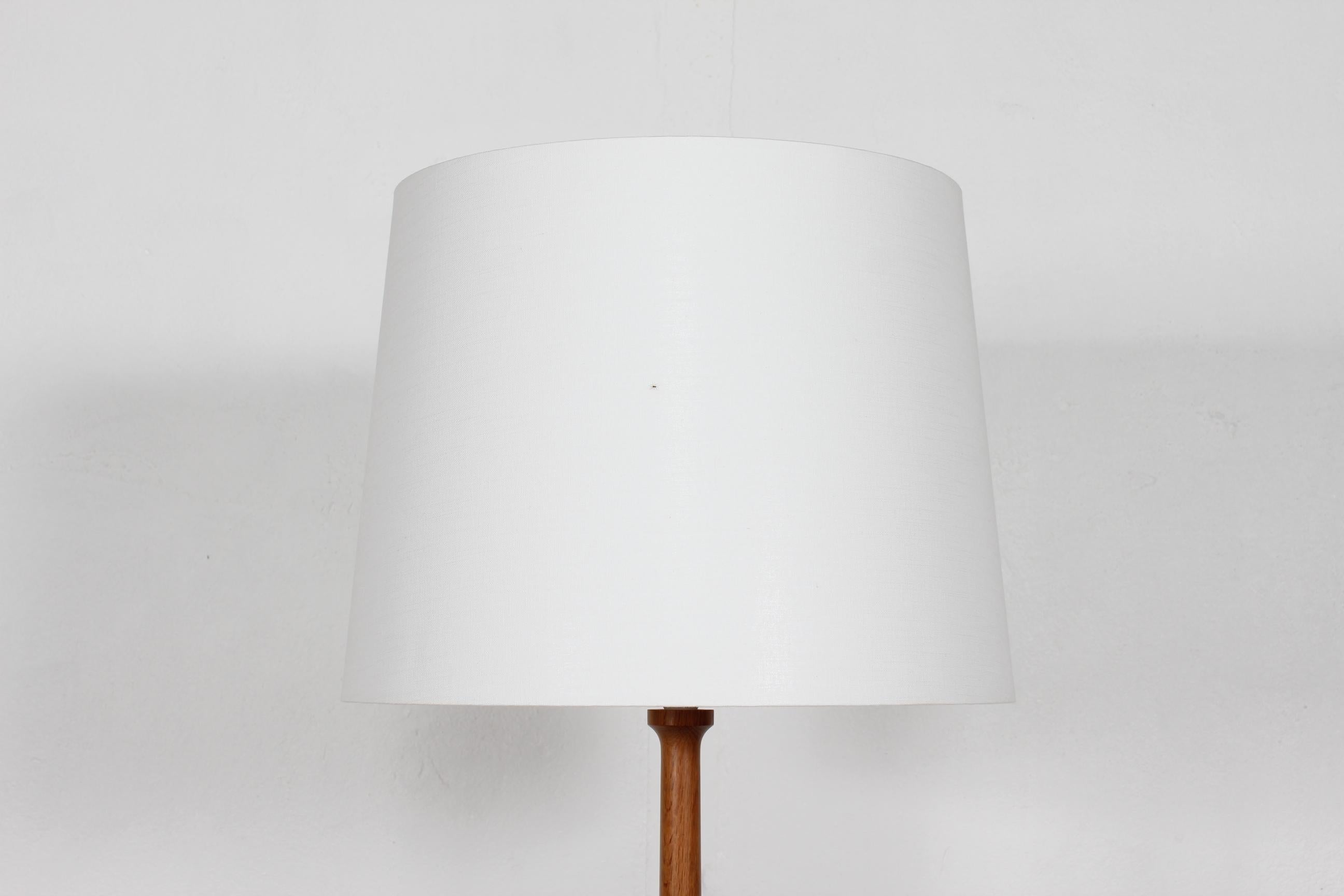 Teak floor lamp by Danish designer Lisbeth Brams manufactured by Fog & Mørup in Danmark.

The lamp base is made of stave glued and hand-turned solid teak with oil treatment.

Included is a new lamp shade designed and made in Denmark. It is made of