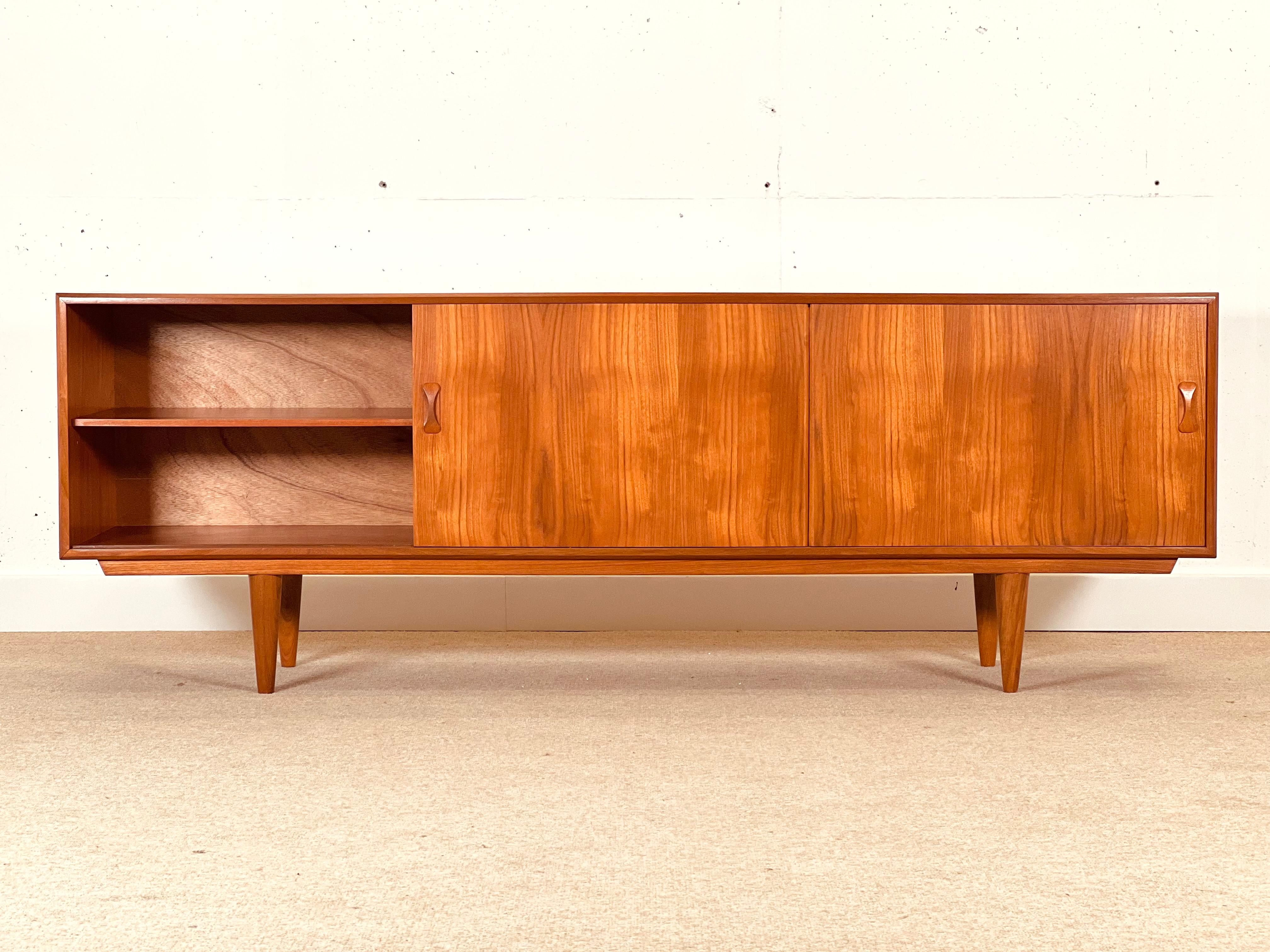 This long sideboard was high-end handcrafted in teak wood by Clausen & Son in Denmark in the early 60’s.

The sideboard is a superb piece with a symmetrical design, a bank of drawers in the middle and a cupboard on each side enclosed by sliding