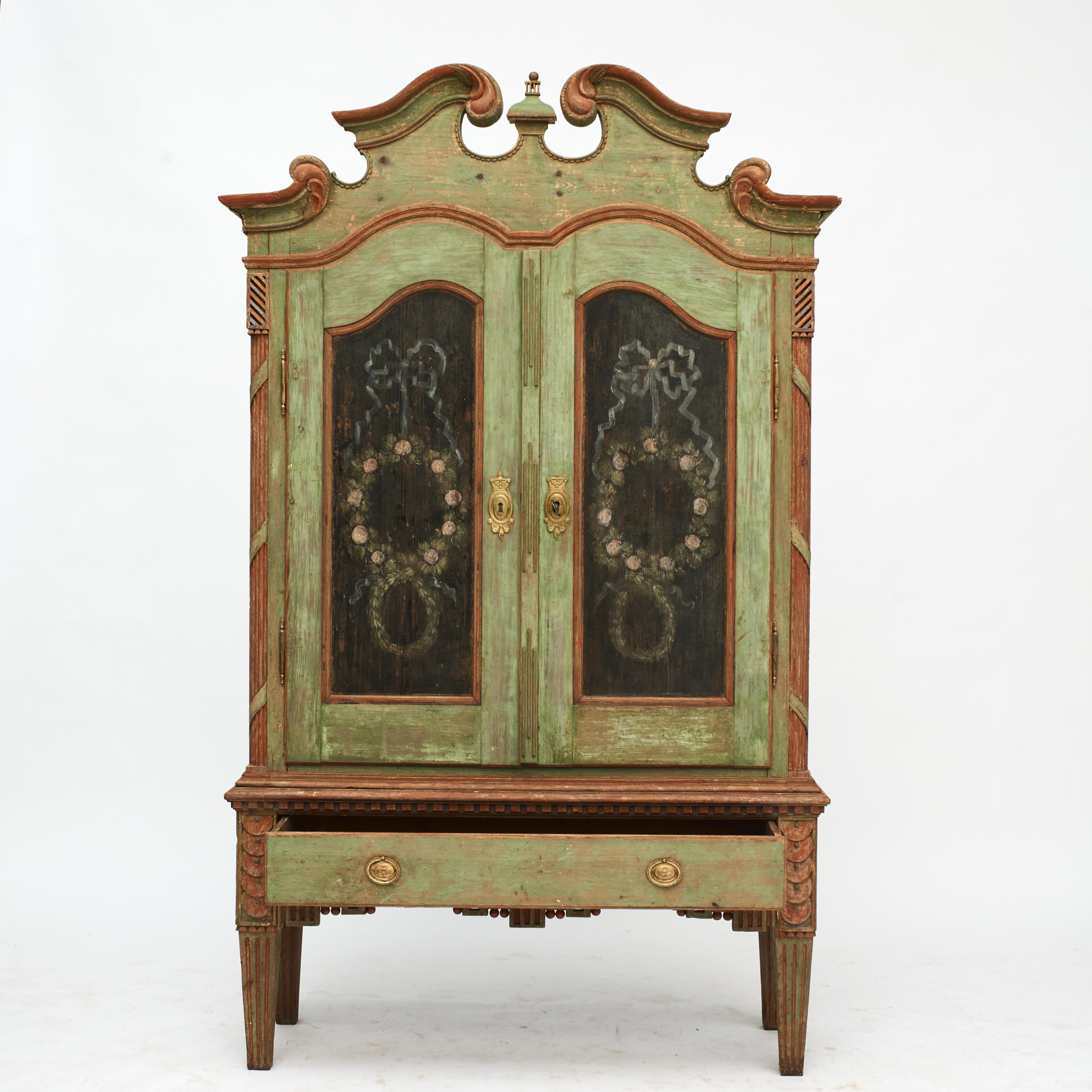Danish Louis XVI cabinet with original paint in soft-hued polychrome colors.
Doors with two main panels depicting flowers and ribbons on a black base.
Many nicely carved details throughout, including a scroll pediment top, pair of fluted quarter