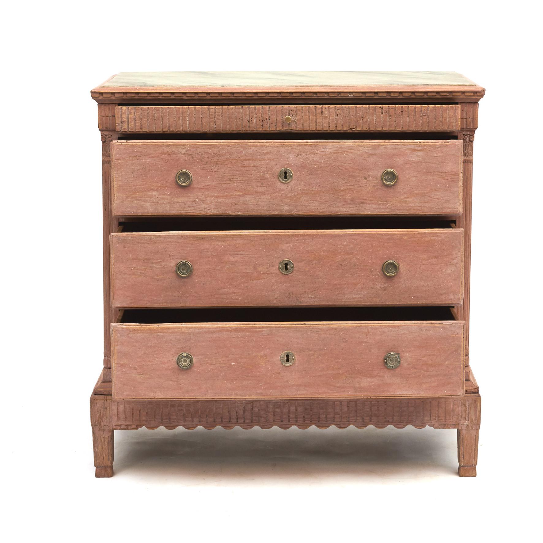 Danish Louis XVI three-drawer commode in light Pompeii red and with a grey faux marble-top.
Carved dental molding frieze above an arrangement of three larger drawers, top drawer with flutings, flanked by fluted columns corners with carved