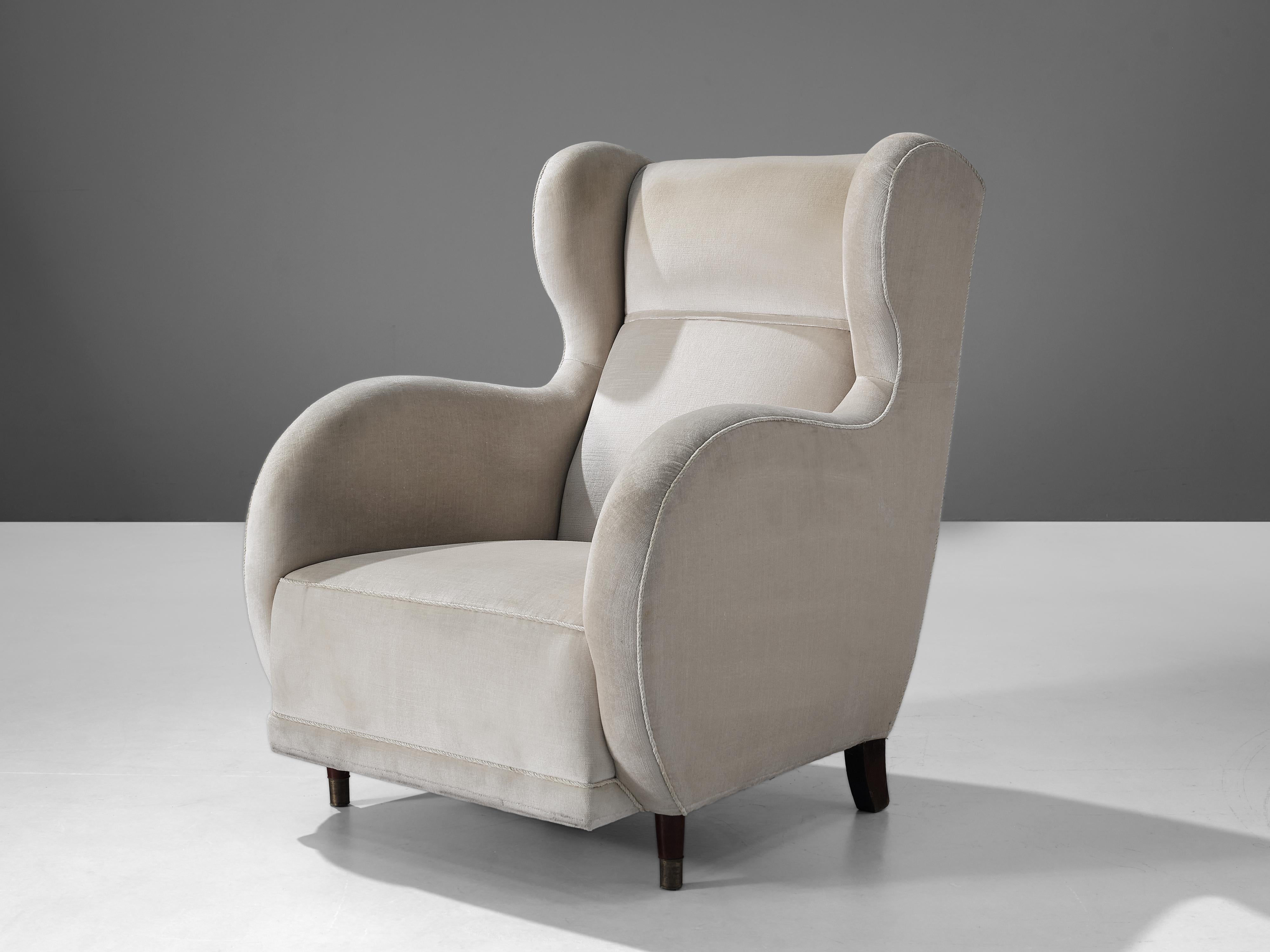 Lounge chair, wood, off-white fabric, Denmark, 1950s

This archetypical wingback chair of the 1950s is both extremely comfortable and pleasing to the eyes. This easy chair with wooden legs features a modest wing and bulky, round armrests. The seat