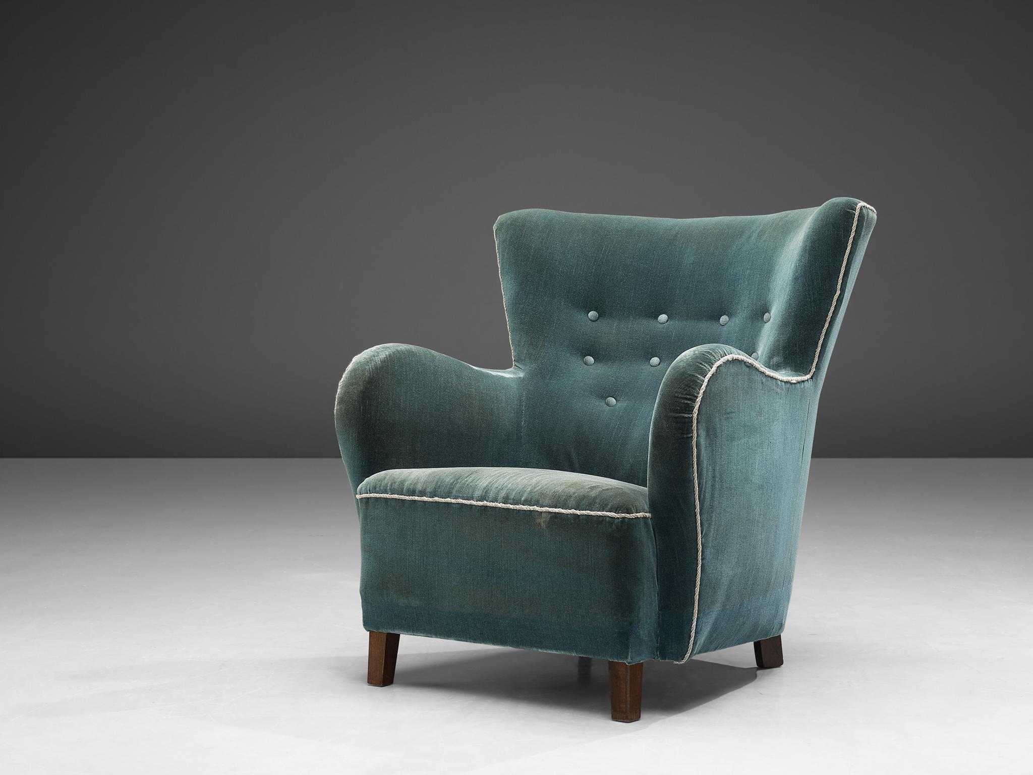 Lounge chair, wood, blue velvet, Denmark, 1950s

This archetypical wingback chair of the 1950s is both extremely comfortable and pleasing to the eyes. This easy chair with stained legs features a wing and tufted backrest. The seat is thick and the