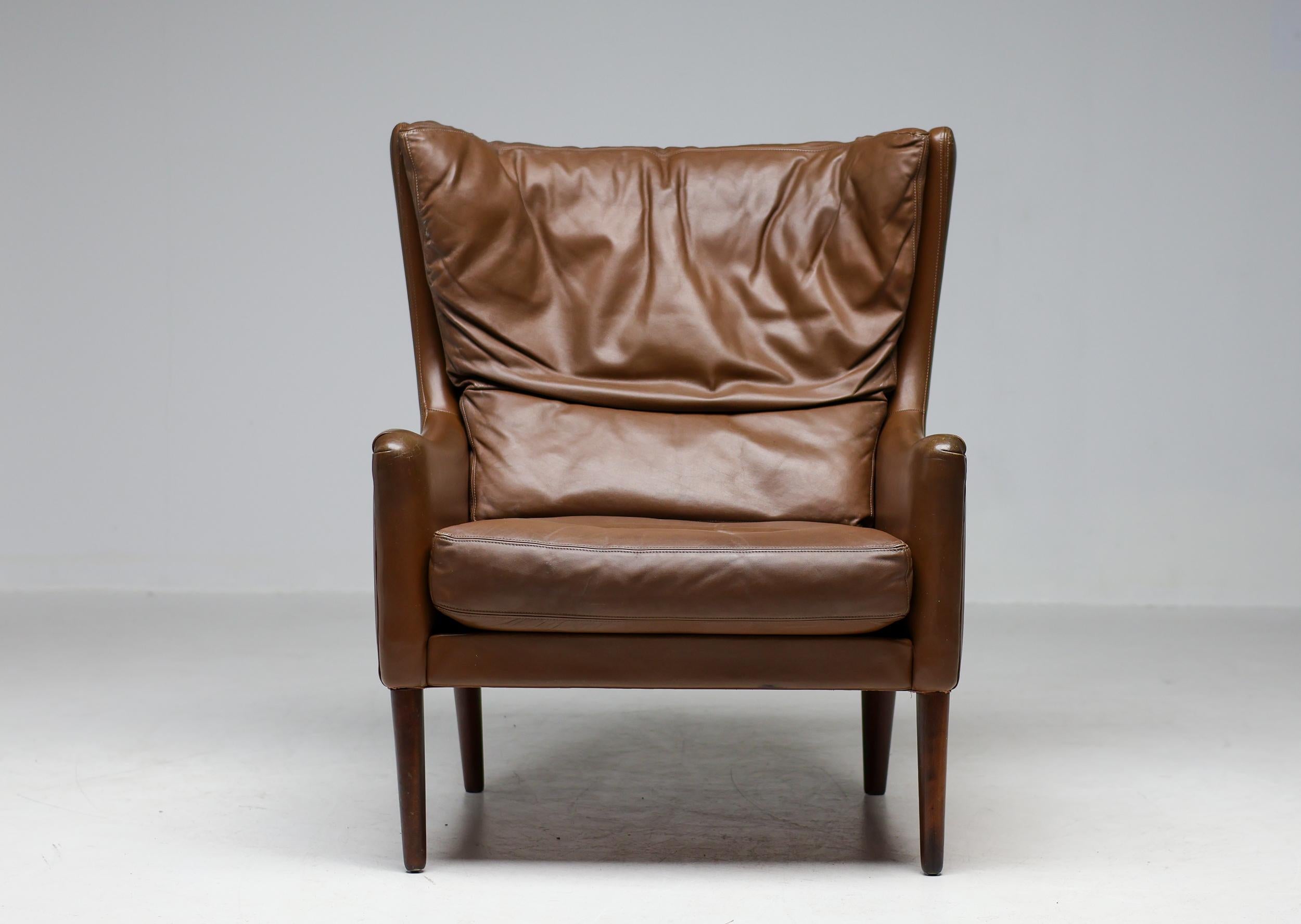 Armchair in beautifully aged natural leather with dark red dye stained beech legs, Denmark, 1966.
 This lounge chair embodies the essence of Danish design. The chair is comfortable, expertly crafted, and boast a simple but very elegant aesthetic