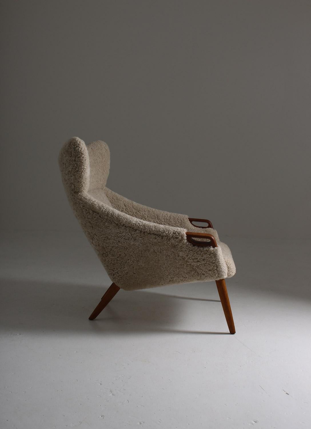 Danish high back wing chair model 55 by Kurt Østervig for Rolschau Møbler, Vejen.
This majestic chair looks great from any angle and, on top of that, is as comfortable as it looks. The details in teak match the off-white sheep skin