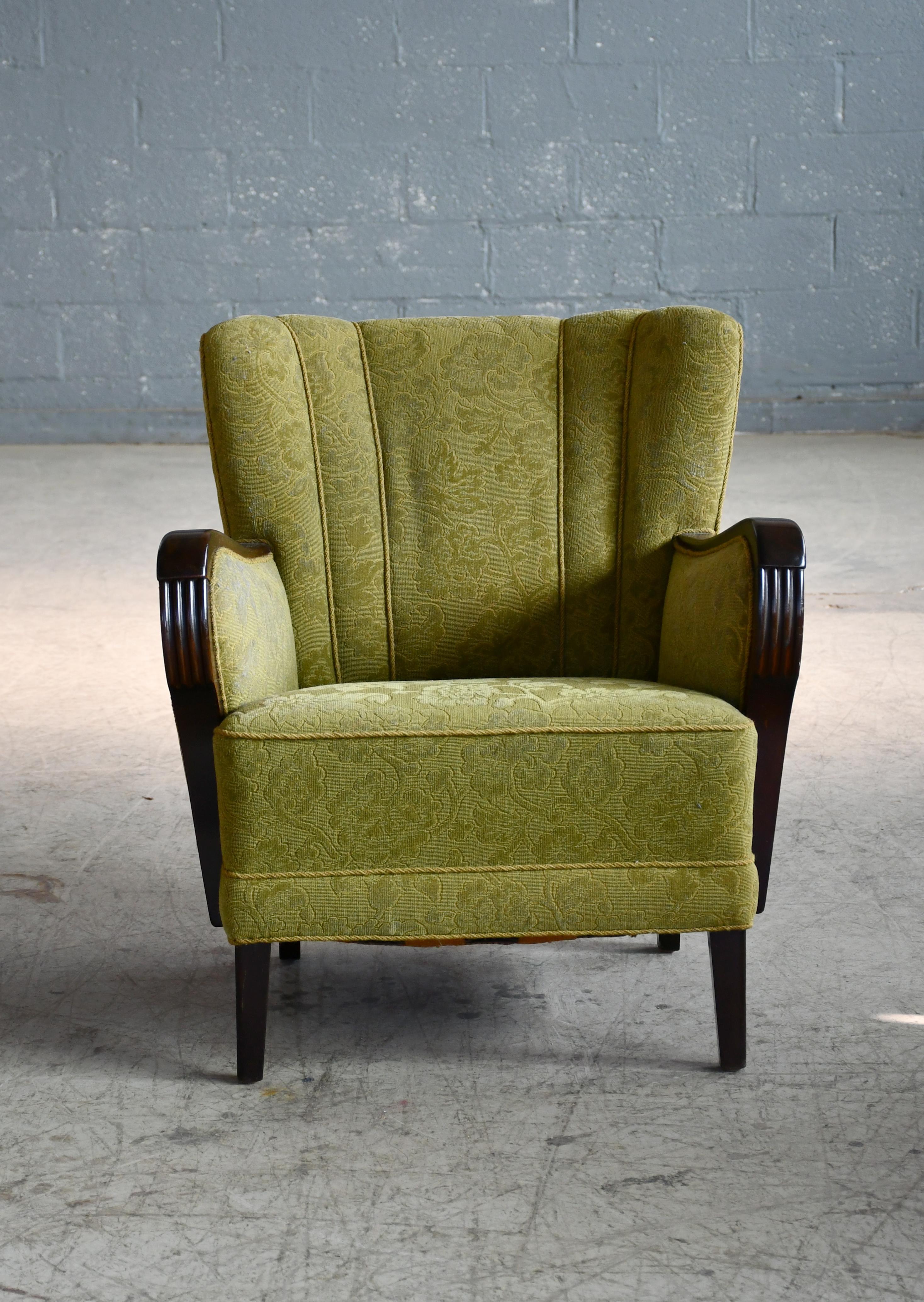Superb Danish lounge chair with carved armrests accents in mahogany probably from the late 1940's or early 1950's. With spring cushions and beautiful armrests with great color. We just love the simple yet very refined elegant design of this chair