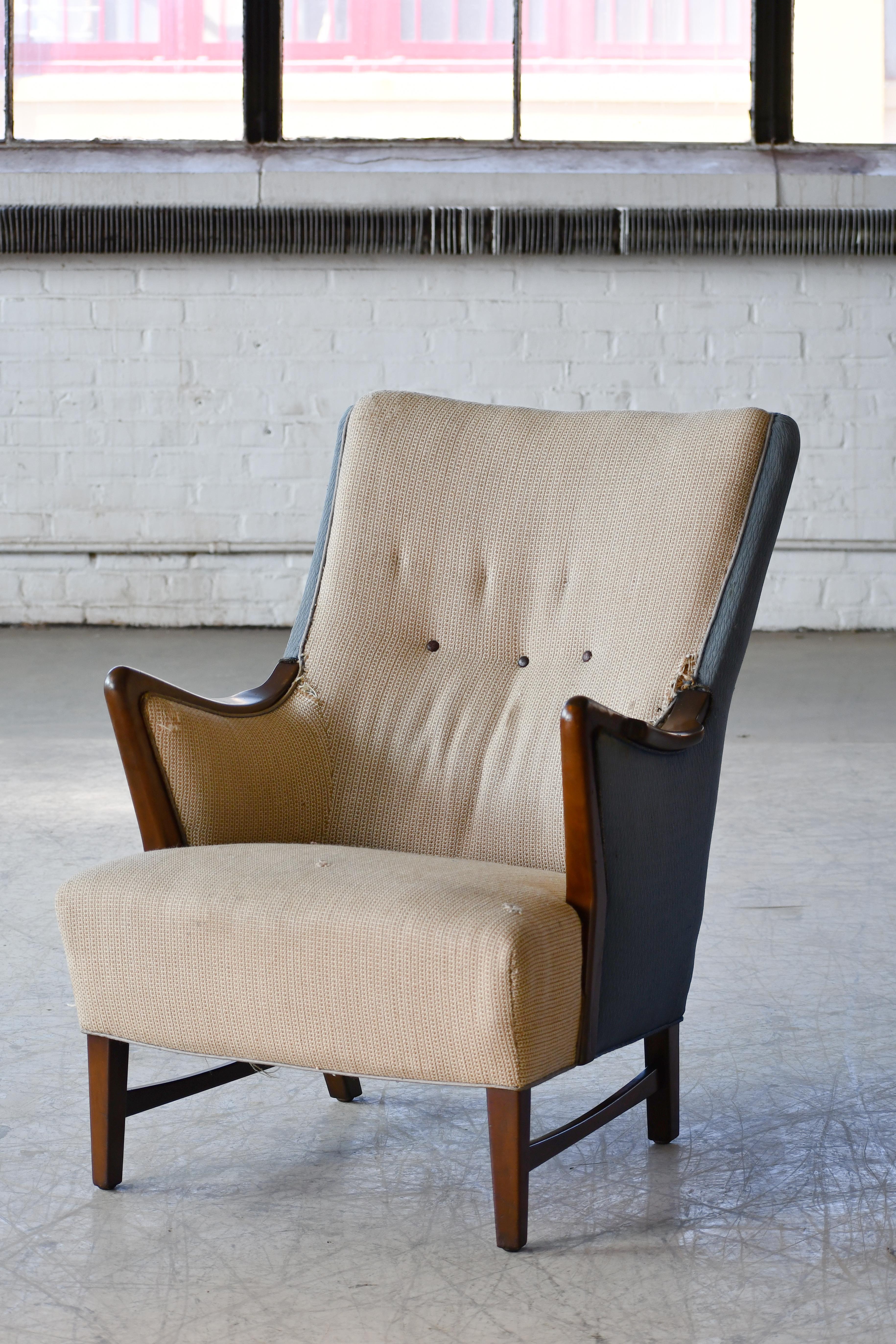 Beautiful Danish lounge chair made in the tradition of Scandinavian makers such as Hjalmar Jackson and Carl Malmsten with wooden armrests and legs with stretcher bars made from Maple adding a lot of elegance and flair. Coil springs in seat and