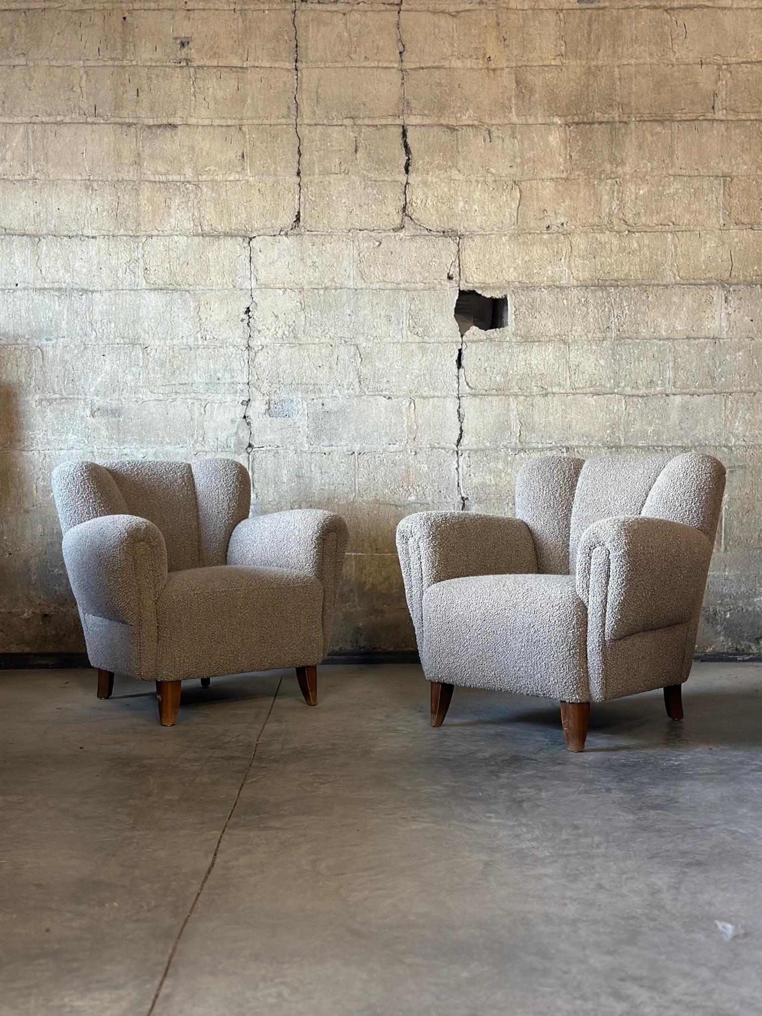 Un par de sillones daneses con respaldo de canal y brazos anchos. Asiento y tacto cómodos. Retapizada en una preciosa lana boucle gris sombra Pierre Frey. 