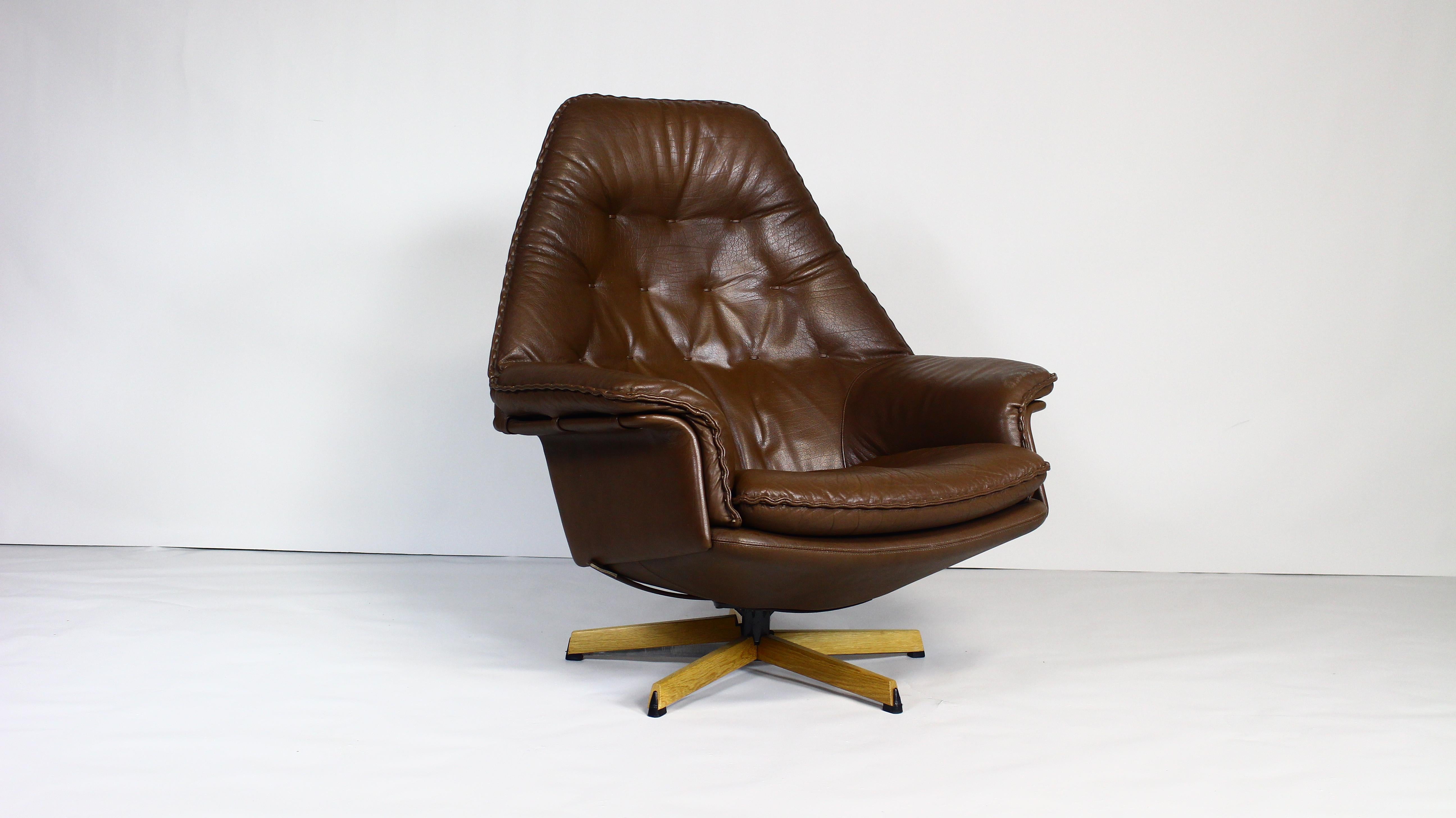 Danish 1960s swivel lounge chair, designed by notable design duo Acton Schubell and Ib Madsen.
The chair is upholstered throughout in genuine textured buffalo leather, which is brown in colour.
The backrest, seat and head cushions feature leather