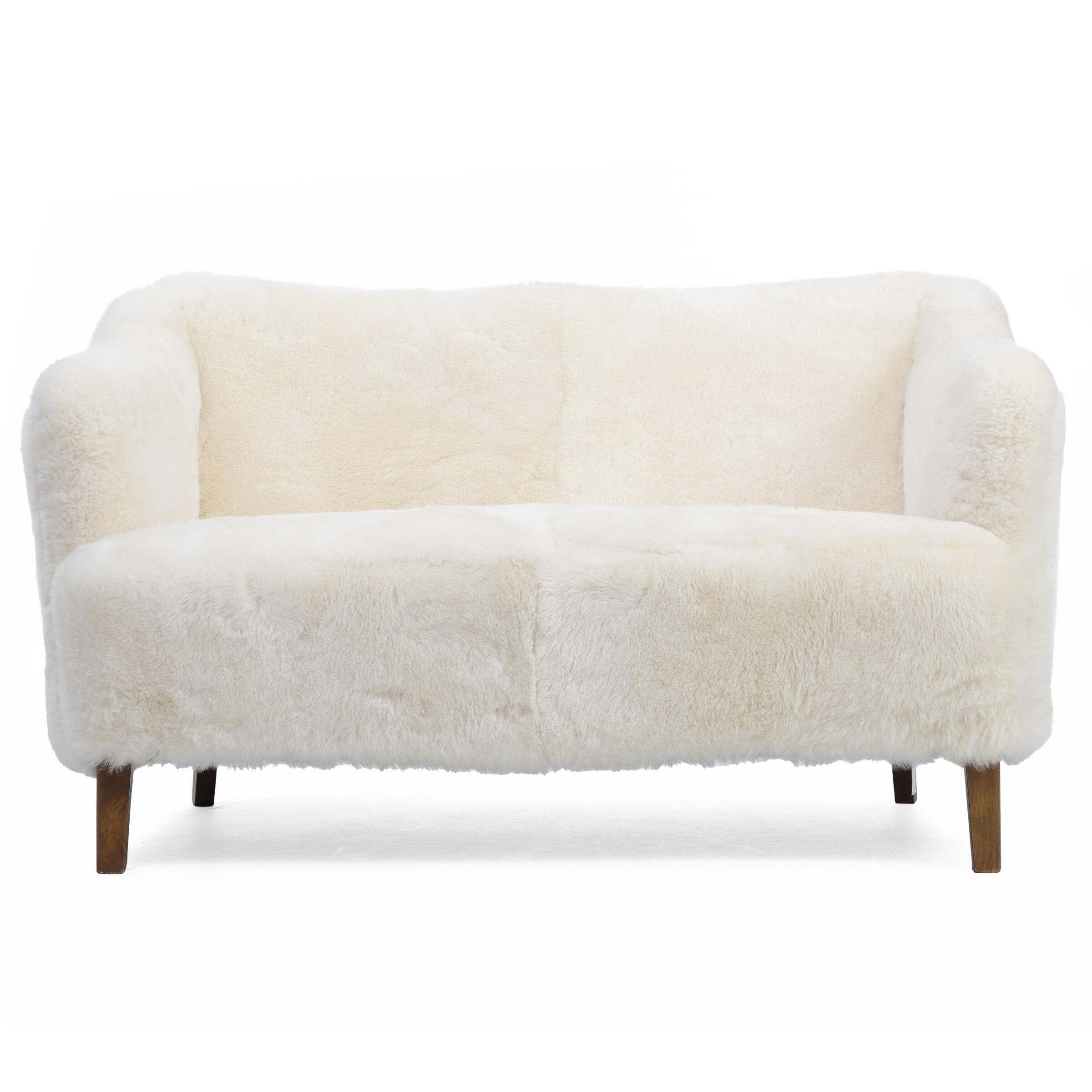 Two-seater sofa with stained beech legs. Upholstered with light and very soft lambswool. Designed 1930–1940s. 

Measures: H. 77 cm. W. 135 cm. D. 84 cm.