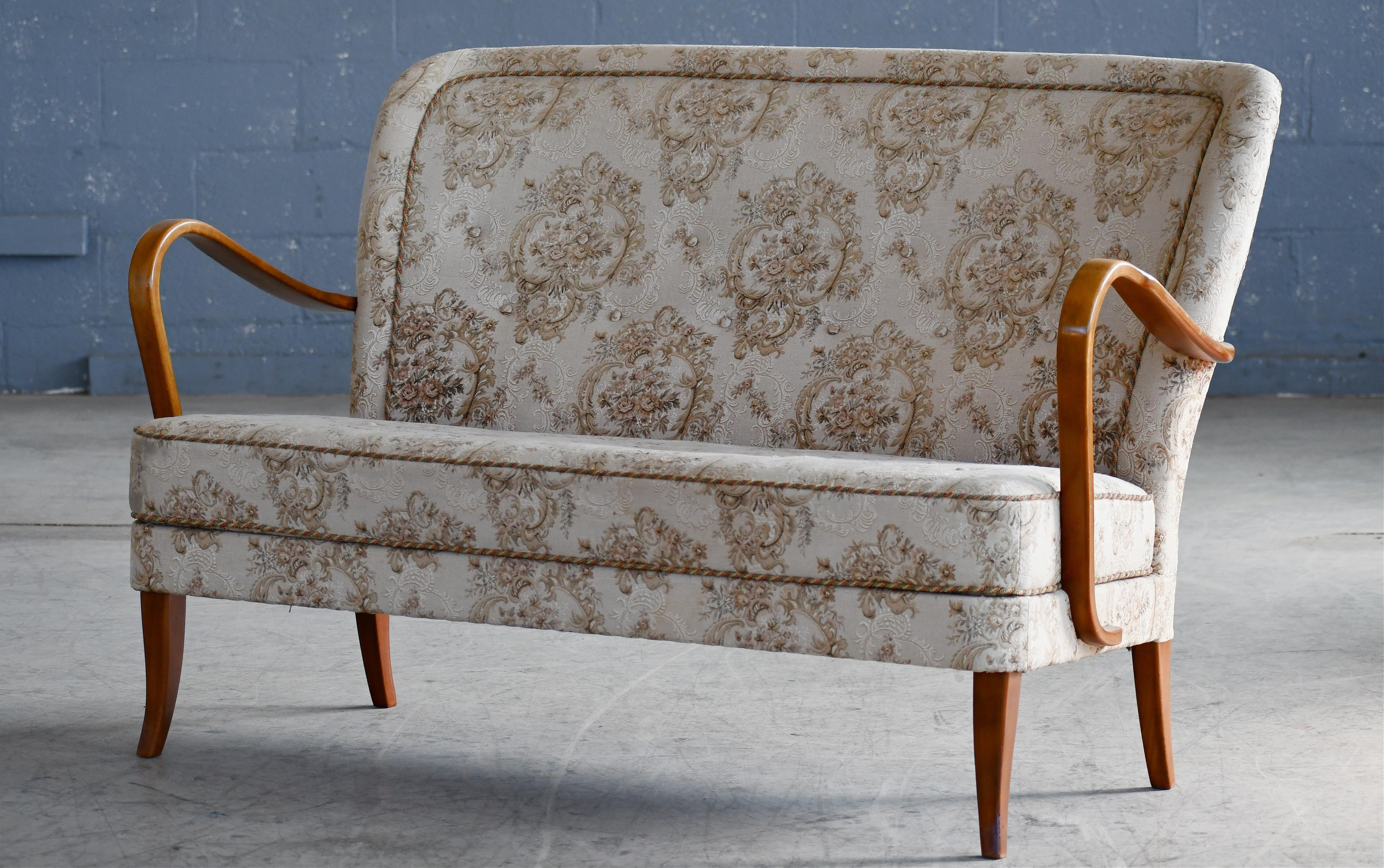 Splendido divano danese della fine degli anni '40 o dei primi anni '50 con molle elicoidali nella seduta e bellissimi braccioli aperti e gambe intagliate in faggio massiccio macchiato con ottime venature e patina. Ci piace molto il design semplice e
