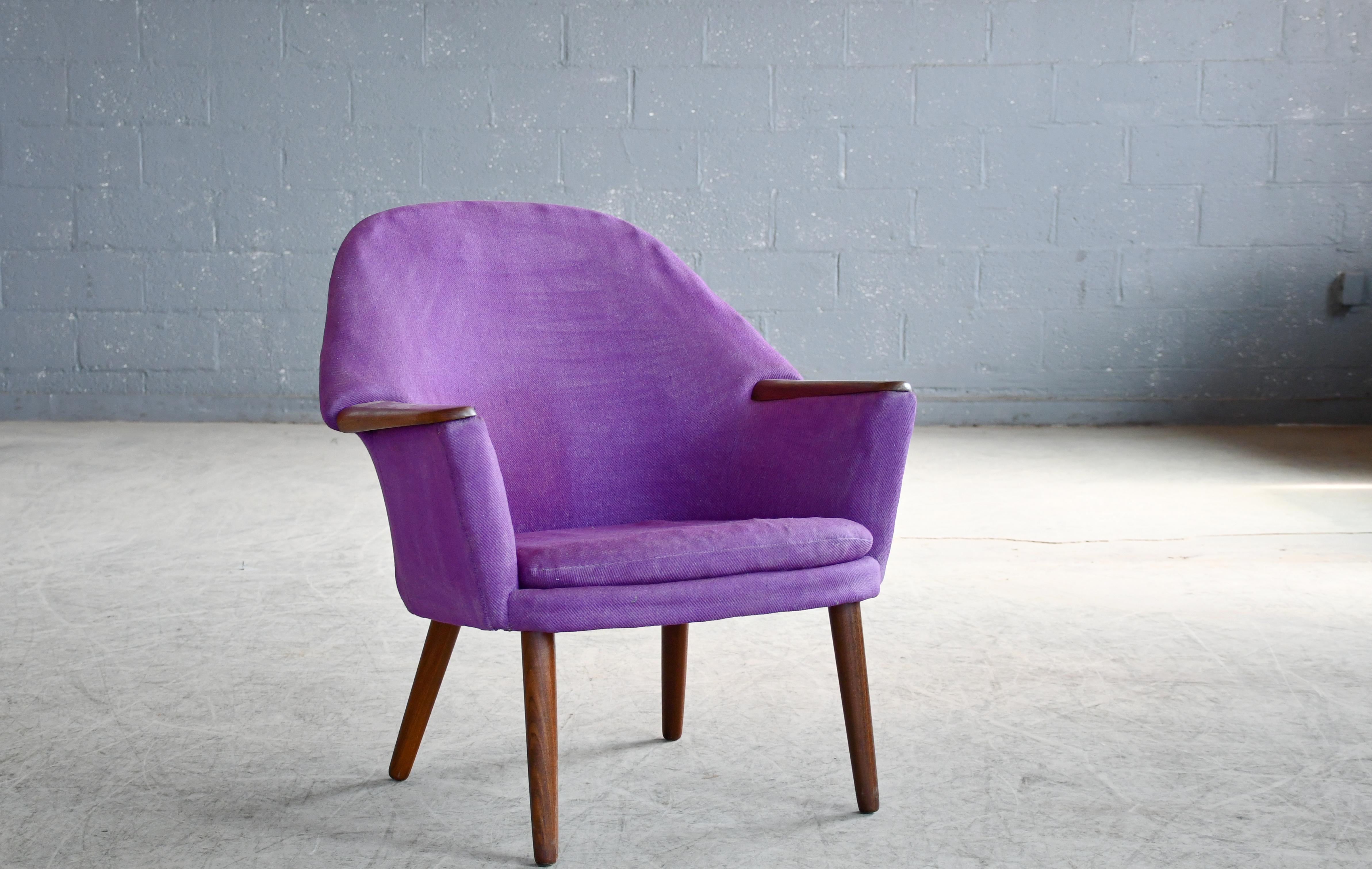 A sculptural and very beautiful 1960s lounge chair with teak accents on the armrests. The chair has some of the same of the same design lines as Hans Wegner's famous Mama Bear chair although a bit more compact. Solid teak armrests raised on legs of