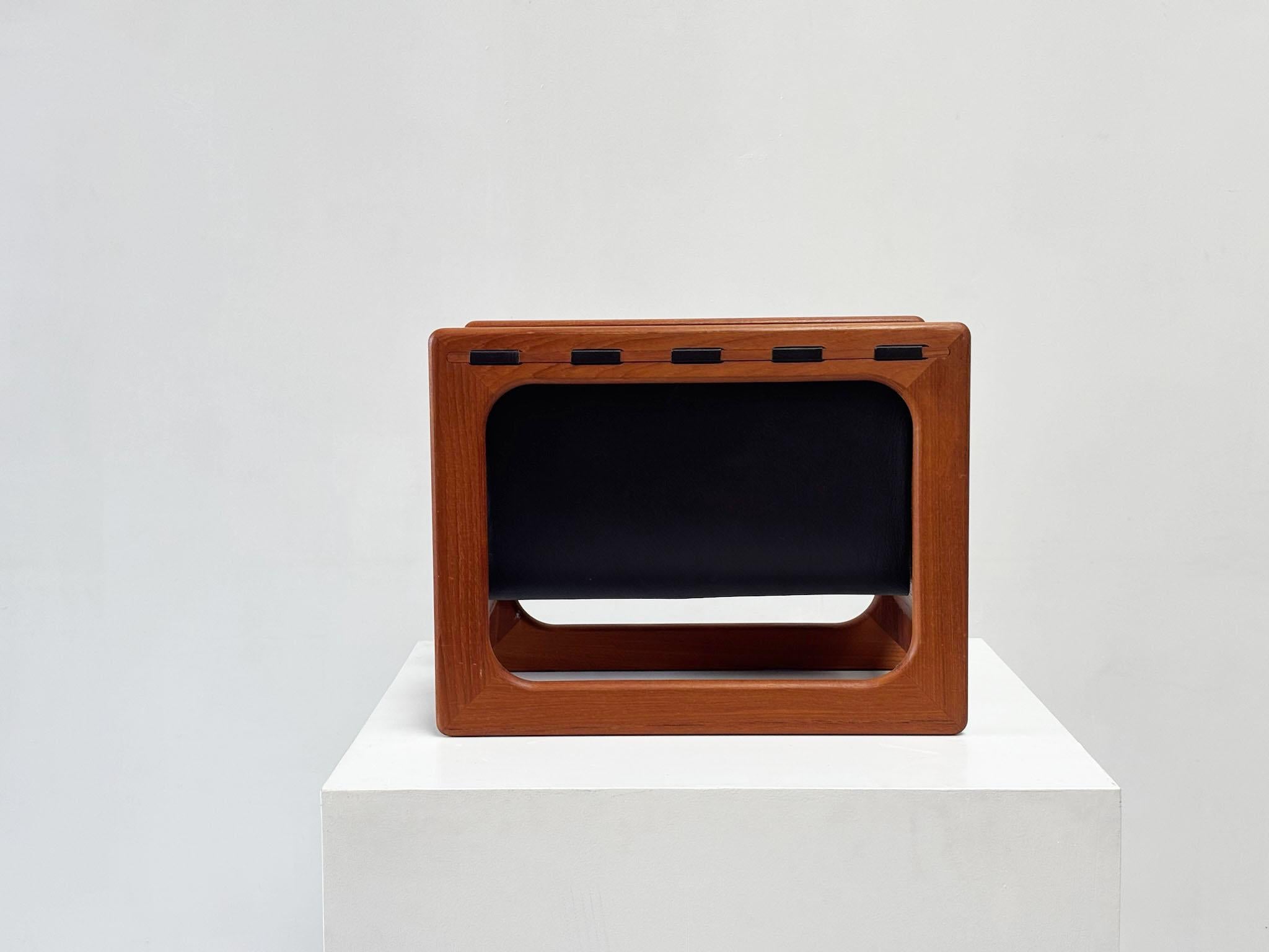 Elegante portariviste danese degli anni '70, disegnato da Aksel Kjersgaard e prodotto da Salin Møbler. La struttura in teak caldo e l'imbragatura in pelle marrone creano un bellissimo contrasto di materiali. Un pezzo d'accento raffinato e funzionale