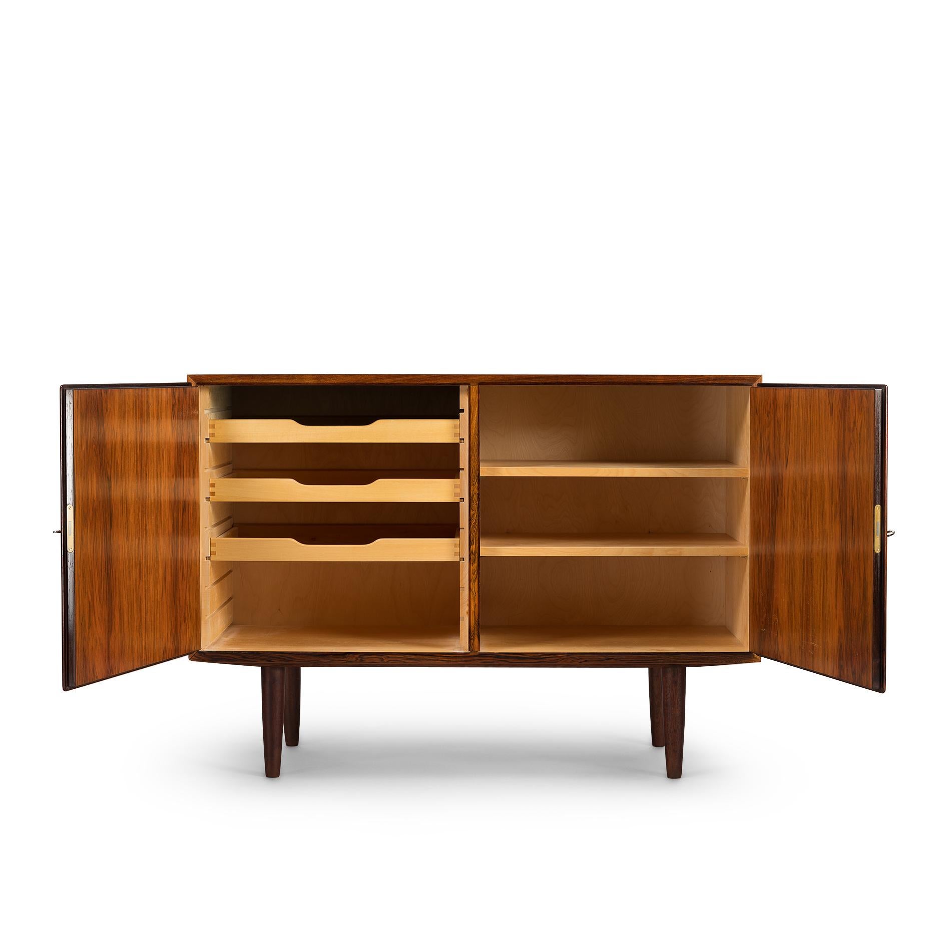 Designed by Carlo Jensen and made by Hundevad & Co. this side board is truly a classic design. Finished in a beautiful Mahogany veneer this cabinet comes with great construction finesse and quality. There are height adjustable drawers on the left