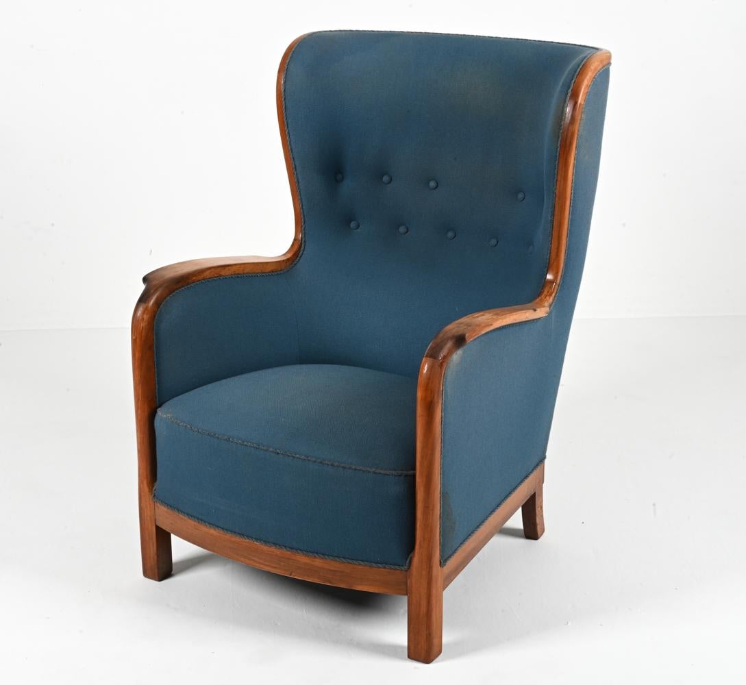 Introducing an exquisite wingback easy chair by the legendary Frits Henningsen, a master of Danish design whose legacy continues to captivate enthusiasts and connoisseurs alike. Dating back to the 1940s, this chair is a timeless embodiment of