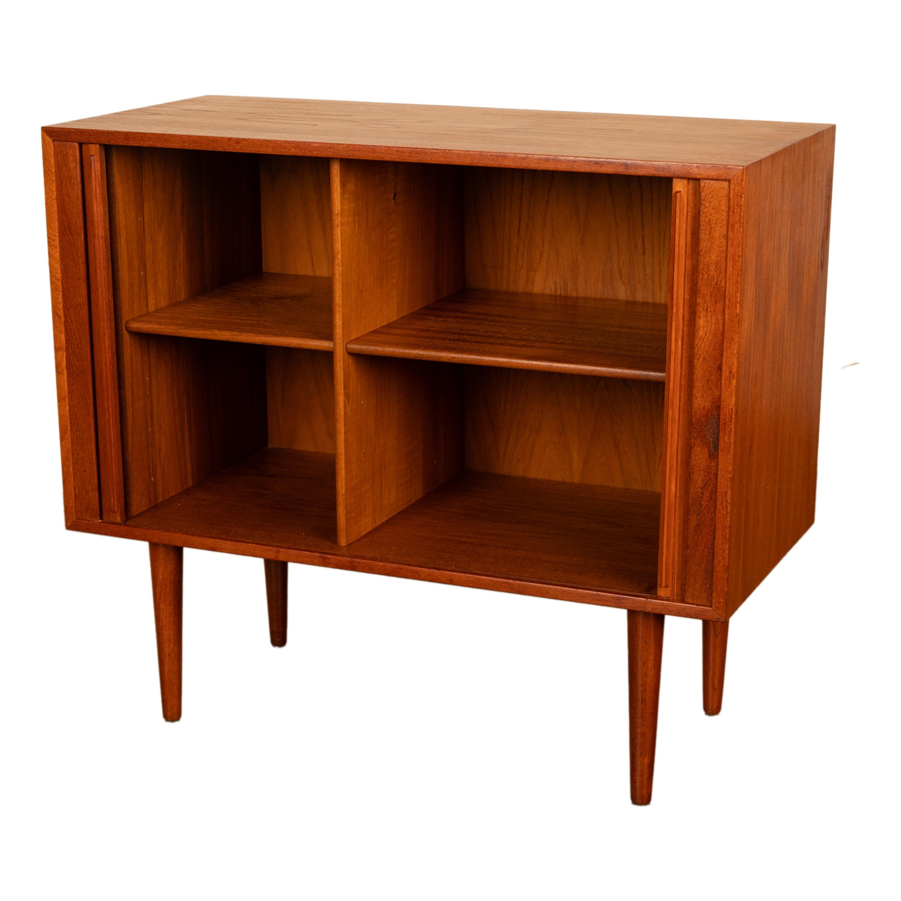 Ein guter kleiner dänischer Mid Century Modern Teakholzschrank mit Rollfront, um 1960, von Kai Kristiansen für Feldballes Møbelfabrik.
Der Schrank hat eine verkleinerte Form und verfügt über zwei Rolltüren, die vier Ablageflächen umschließen. Der