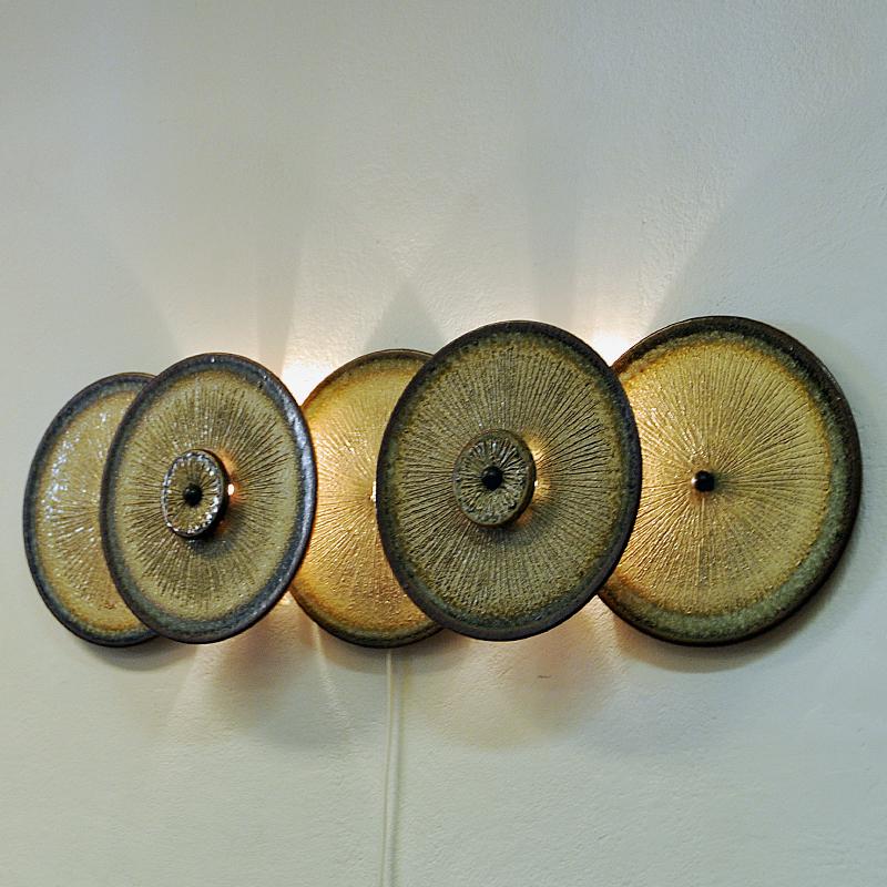 A stunning wall light sculpture of five ceramic plates by Noomi Backhausen and Poul Brandborg for Søholm Keramik, Bornholm Denmark in the 1960s. Beautifully glazed earth colored stoneware with rippled texture in front. Beautiful light flowing out