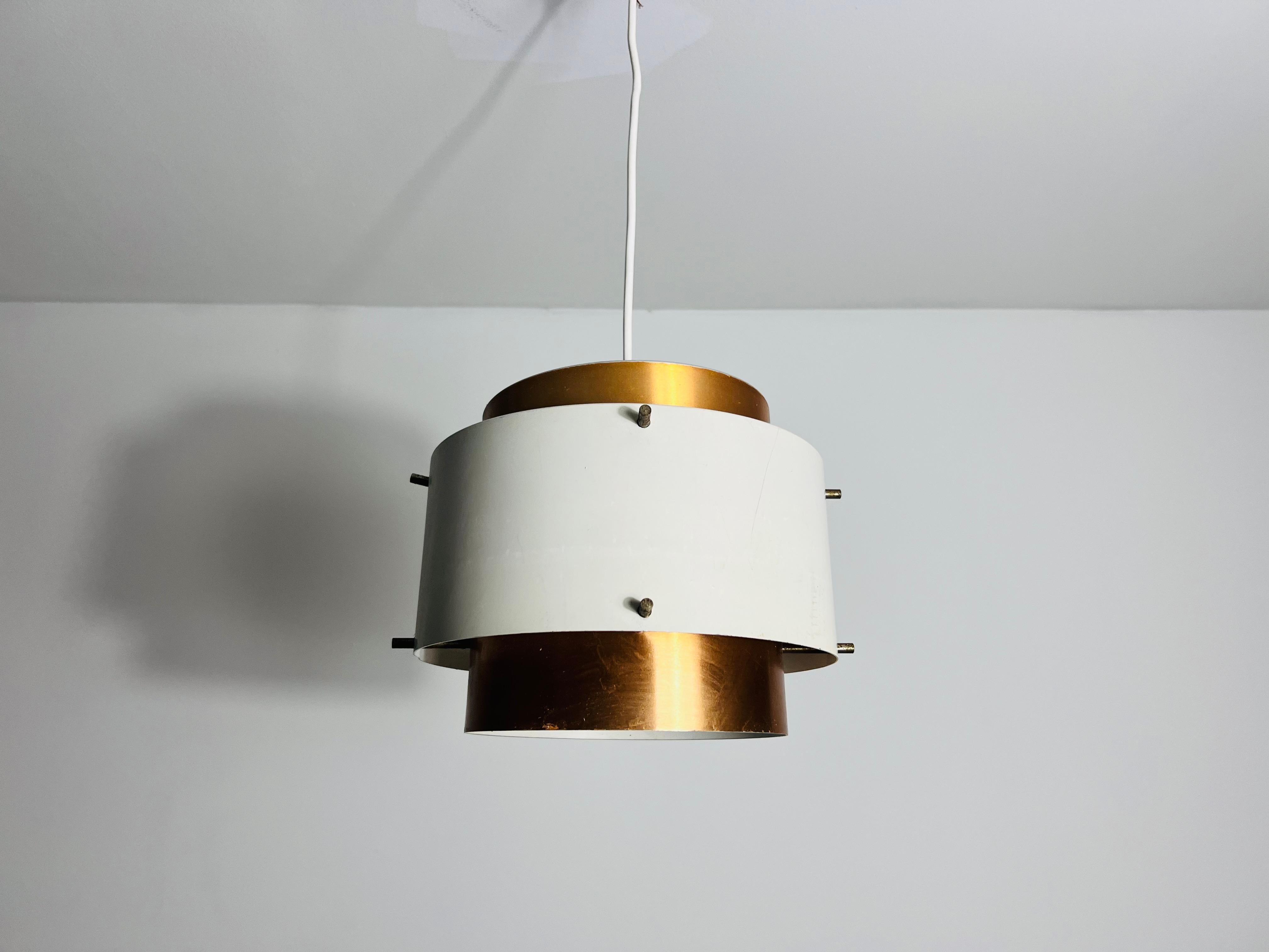 Questa lampada a sospensione vintage, realizzata in Danimarca negli anni '70, esemplifica l'iconico design scandinavo dell'epoca. Realizzata in alluminio color rame, la lampada presenta una silhouette elegante e stratificata che riflette modernità
