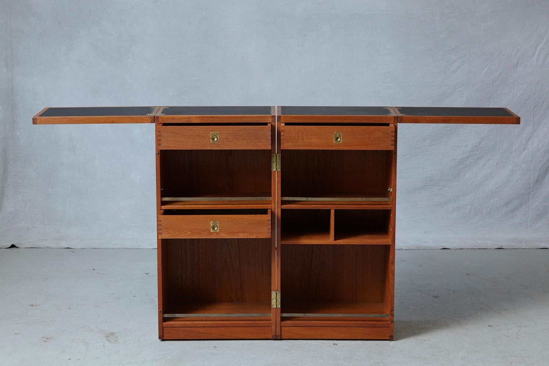 'Captain's Bar', an exceptional teak and brass bar on casters by Danish designer Reno Wahl Iversen for Dyrlund, circa 1960s.
The metamorphic brass hinged cabinet opens to an interior fitted with three dovetailed drawers with brass hardware, the two