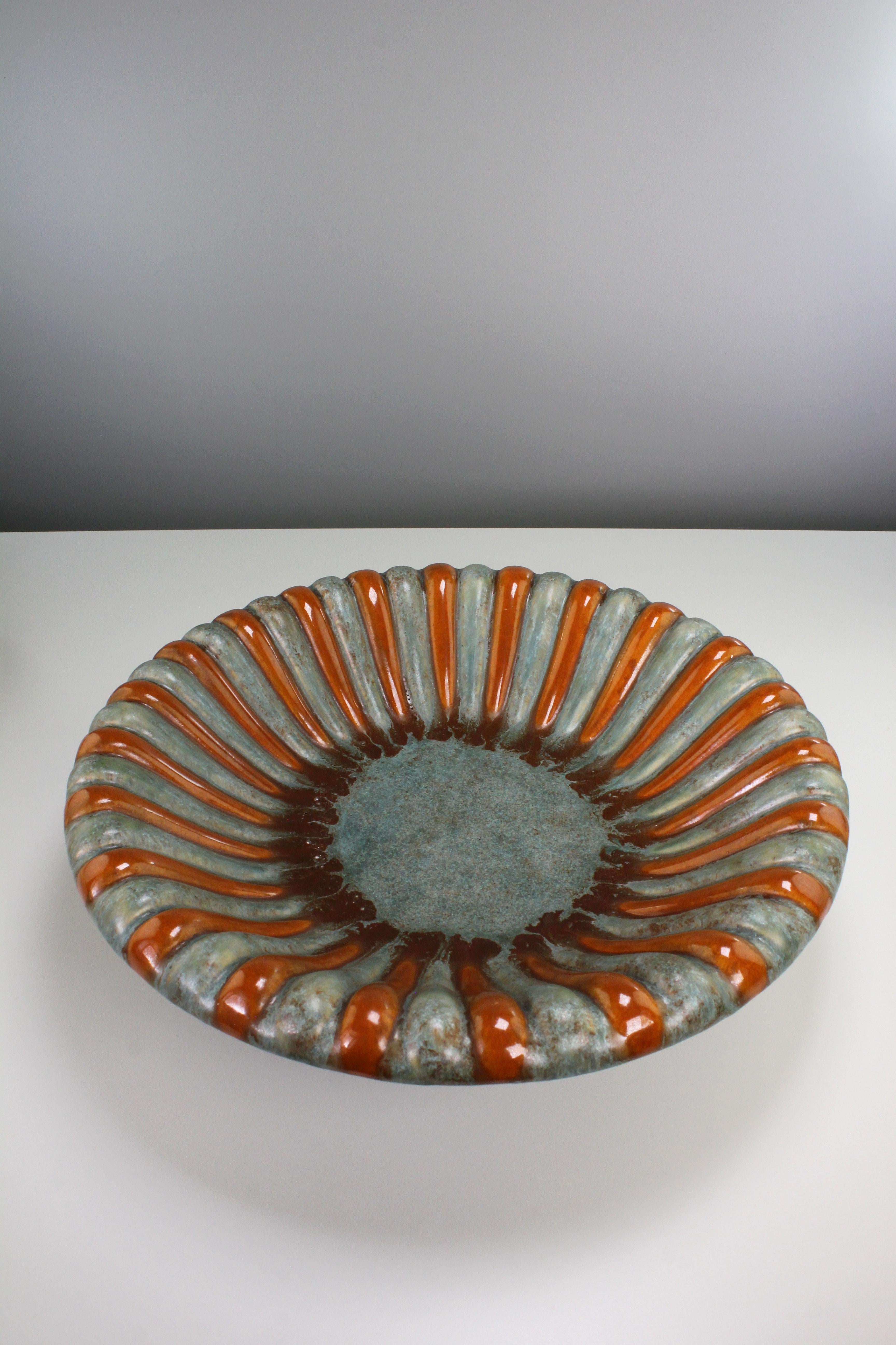 Striking Danish Art Deco handmade ceramic decorative bowl by Michael Andersen & Son. Vibrant orange, umber and seafoam green glaze over relief wave-like striped pattern from centre to edge. Manufactured on the island of Bornholm in the early 1940s.