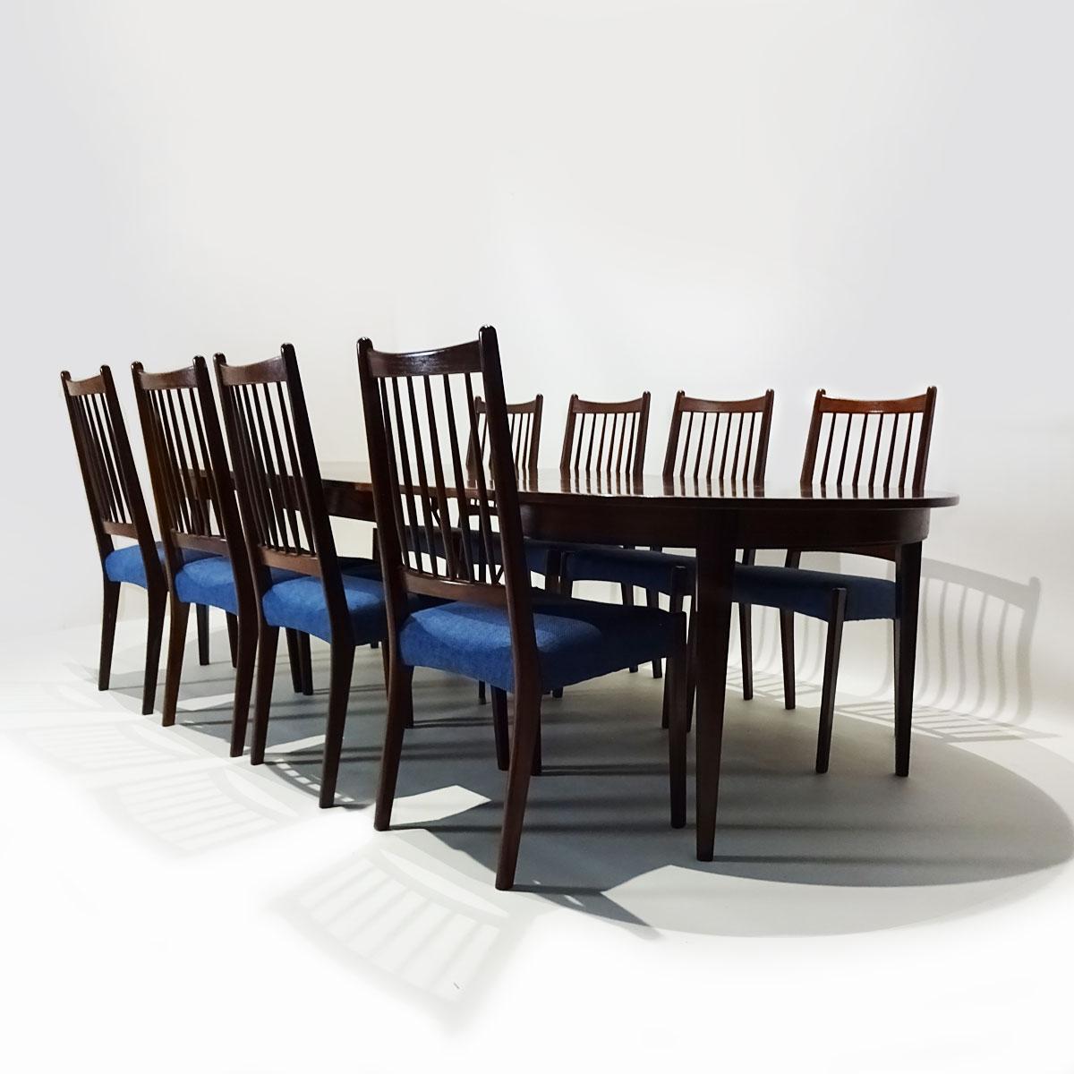 A large extending 10-seat Gunni Omann Model 55 rosewood extending dining table matched to 8 Arne Hovand Olsen dark teak and blue fabric rail back chairs.

Produced by Omann Jun Mobelfabrik in the 1960s this very practical extending dining table can