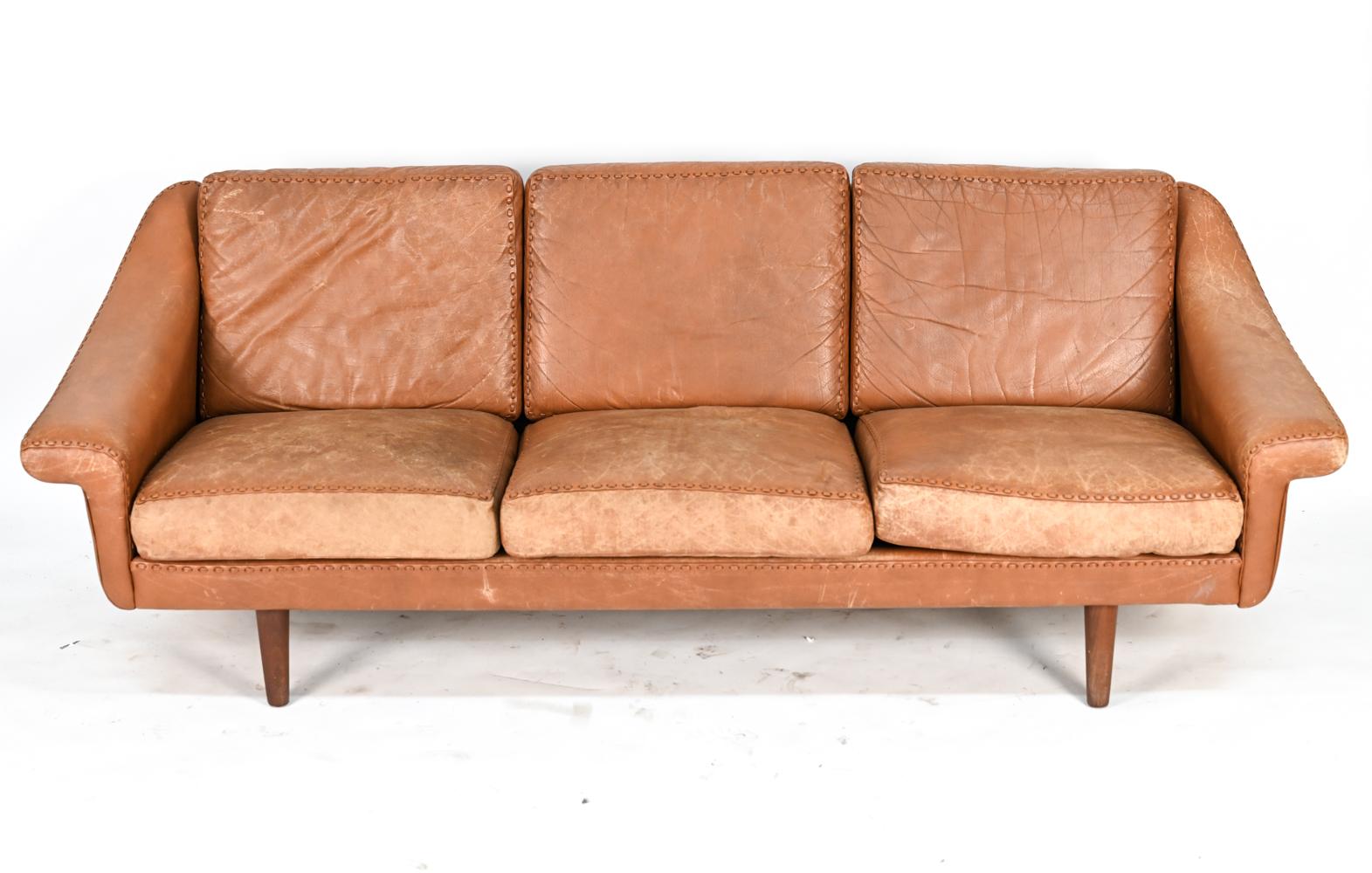 A Danish mid-century three-seater sofa upholstered in handsomely patinated cognac leather with interesting leather stitch detail, De Sede Style. 