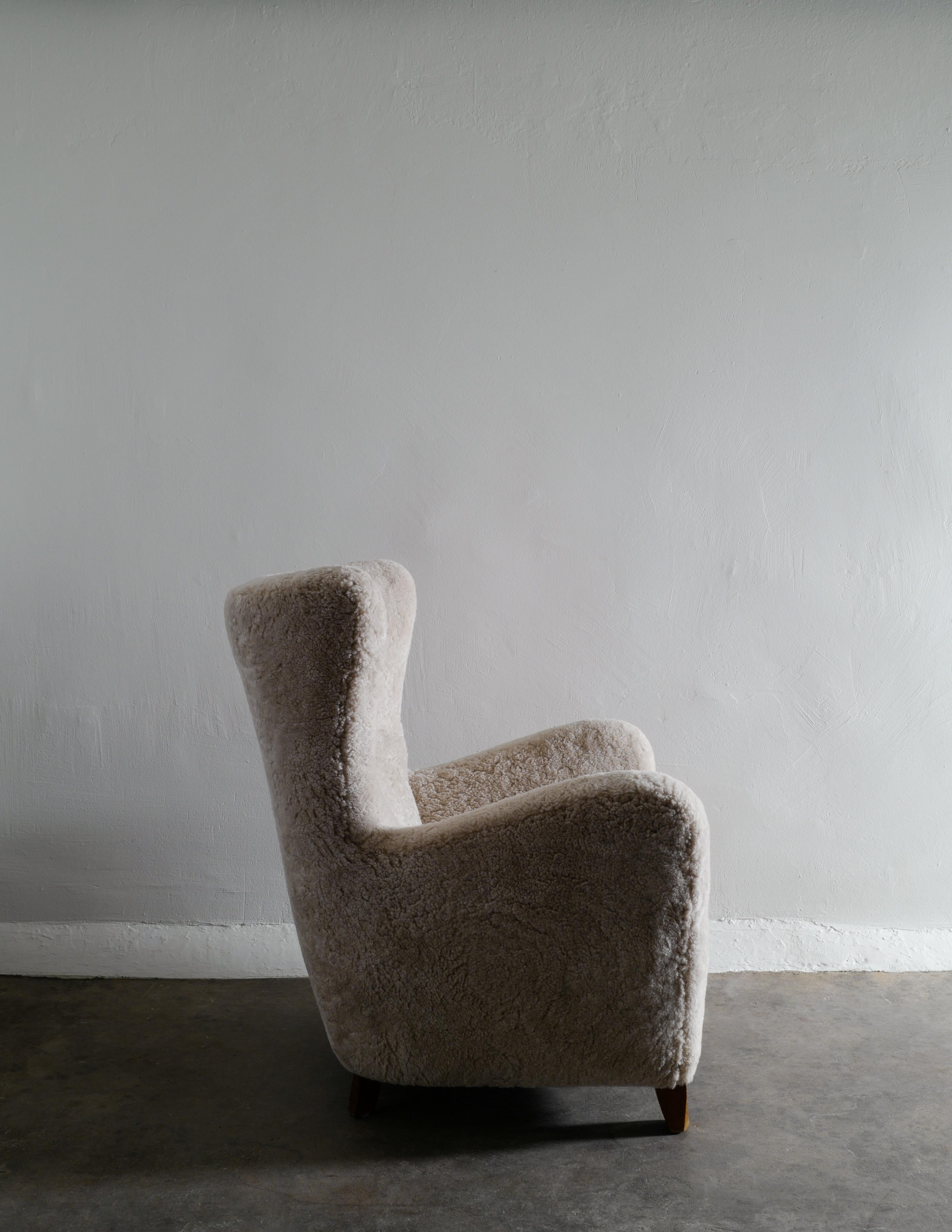 Rare Danish wingback easy armchair in style of Fritz Hansen produced in Denmark around 1940s. Newly restored and upholstered in a soft off white colored sheepskin and in great vintage and overall condition. 

The first picture really describes the