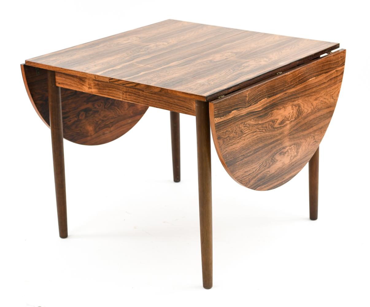 A gorgeous Danish midcentury dining table in the style of designer Arne Vodder. This table is expandable to accommodate a large family for daily use or many guests on special occasions. Crafted of high quality rosewood with a bookmatched veneered