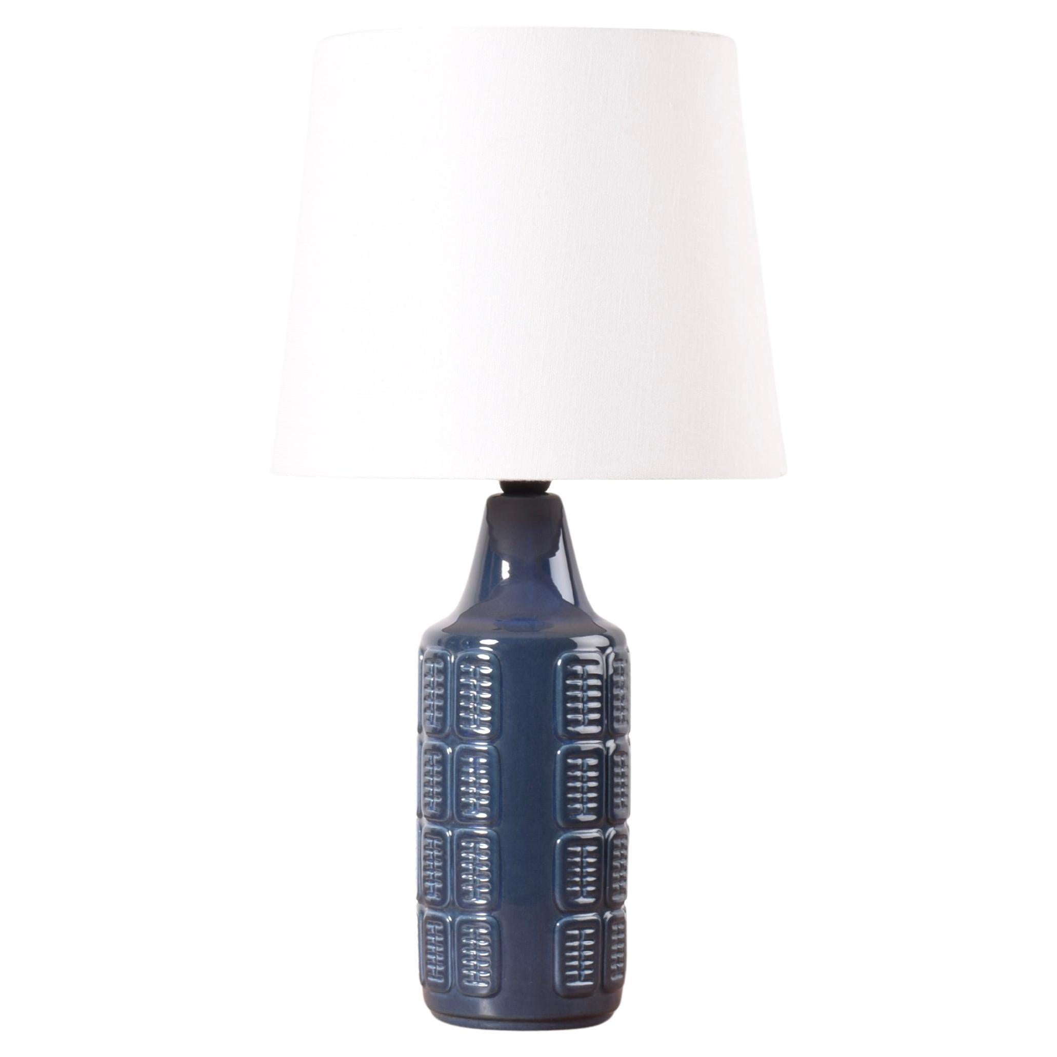 Table lamp by Einar Johansen for Søholm Stentøj, Denmark, circa 1960s.
The lamp has shiny blue glaze over an embossed repeated graphic decor. 

Included is a new lamp shade designed and made in Denmark. It is made of woven fabric with some texture