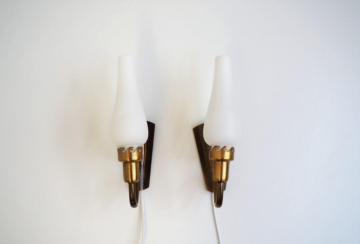 Set of 2 brass sconces with white opaline glass shades made in the 1940s most likely by the Danish company Fog & Mørup.

The brass parts have great natural patina and a decorative pattern where the glass shades are mounted. The glass shades are