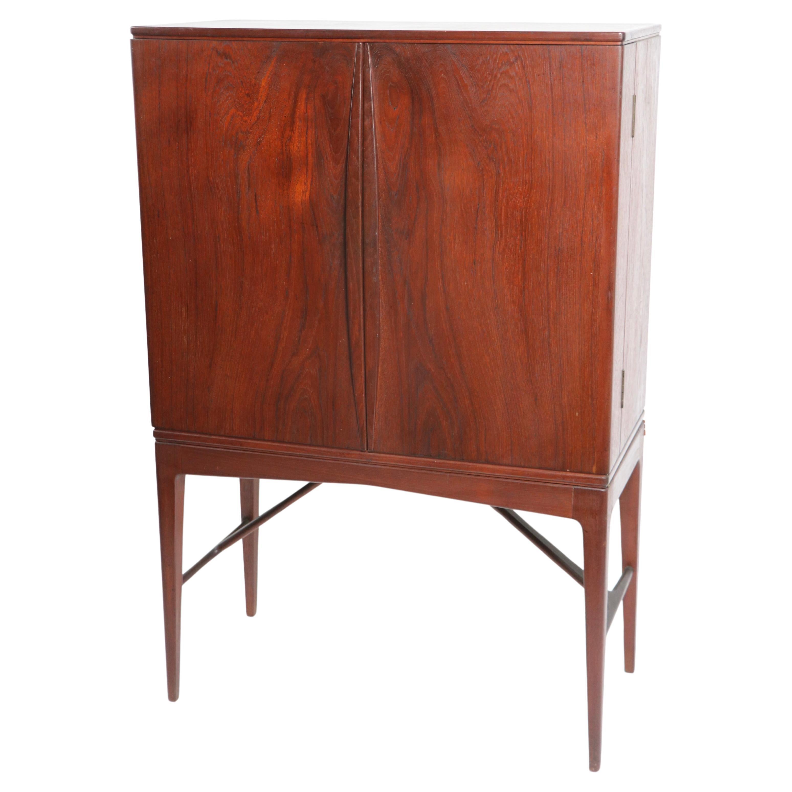 Exquisite Danish Mid Century Modern dry bar cabinet in very fine, original condition. The bar cabinet features two doors, which open to reveal two glass shelves, the doors each have two trays for bottles etc. Top quality design, and construction.